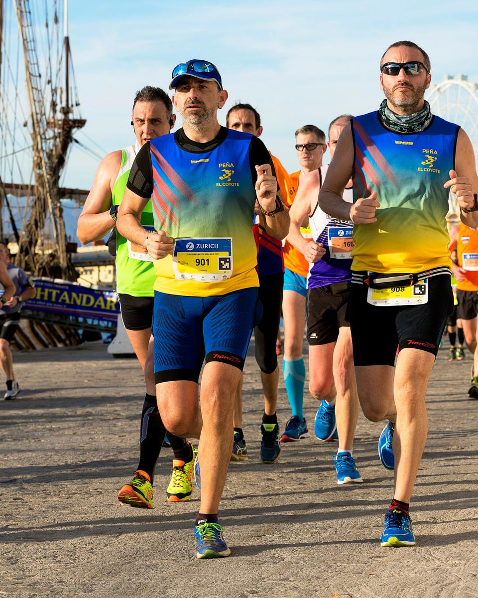 Løbere i maraton langs havnepromenaden i Málaga med palmer i baggrunden