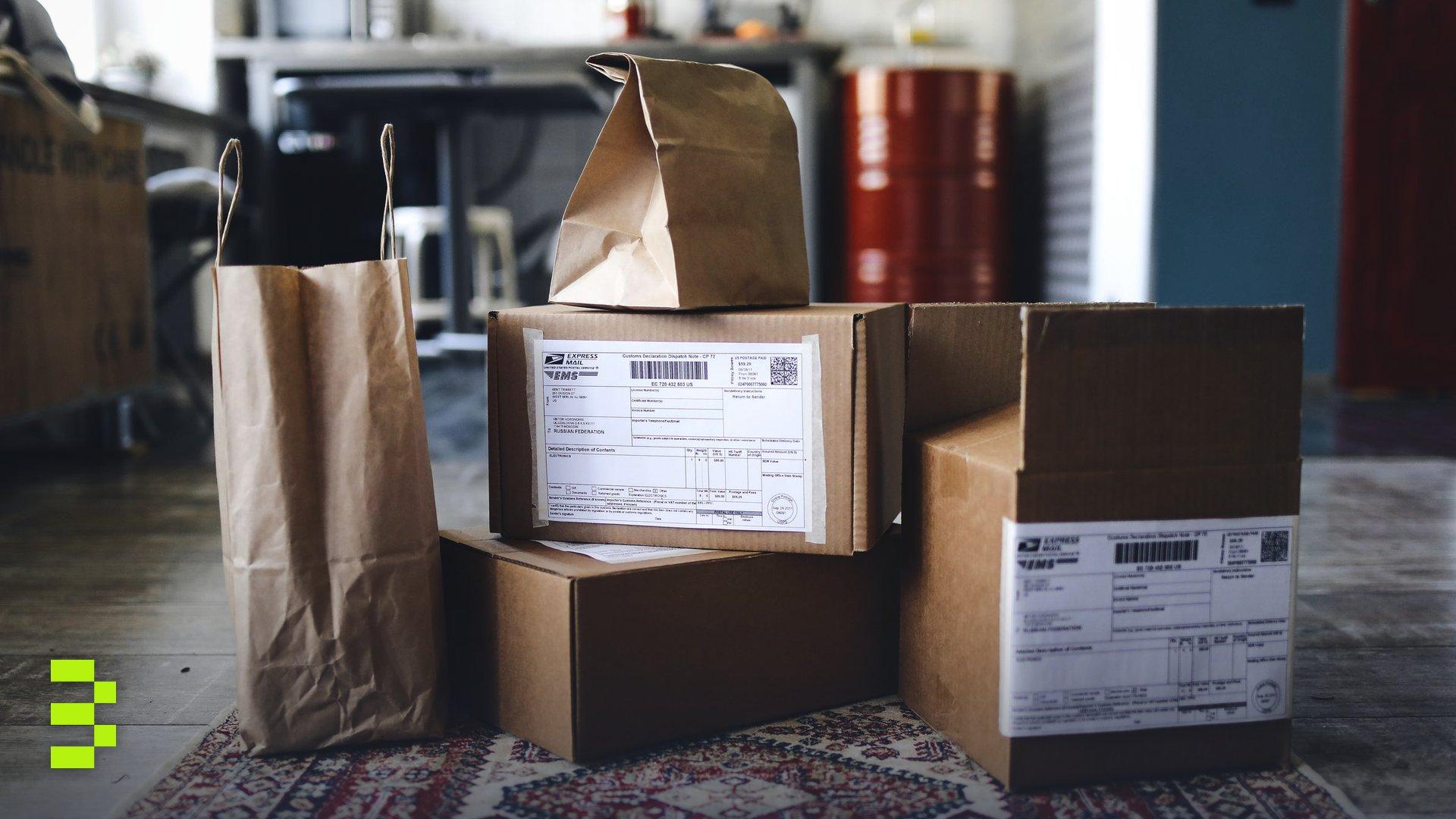 A collection of cardboard boxes and paper bags on a patterned rug in a home setting.