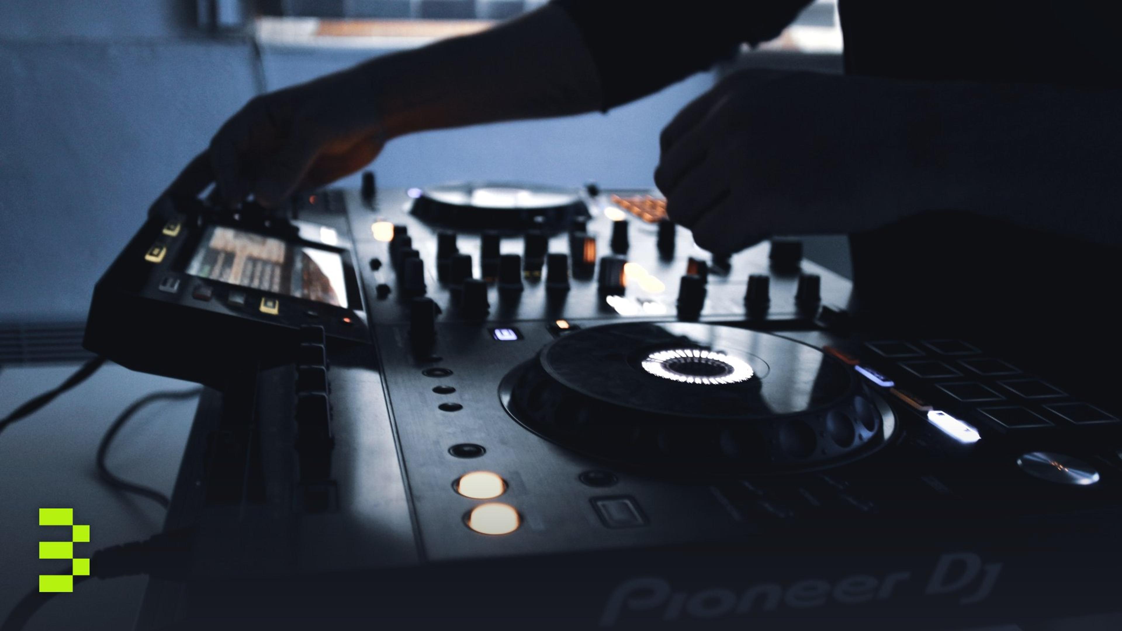 Close-up of DJ equipment in action during a mixing session in a dimly lit room.