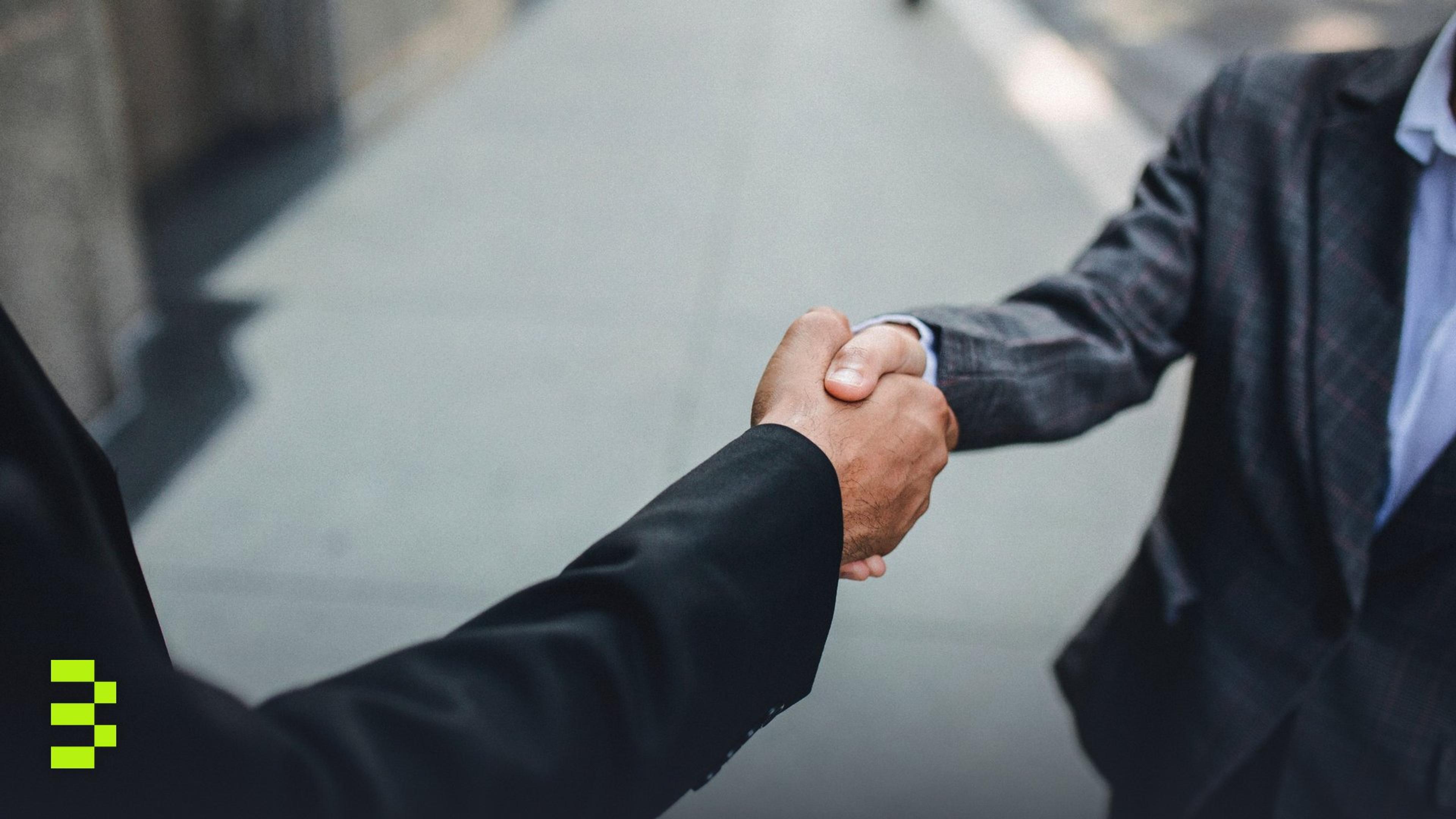 Close-up of two businessmen shaking hands outside.