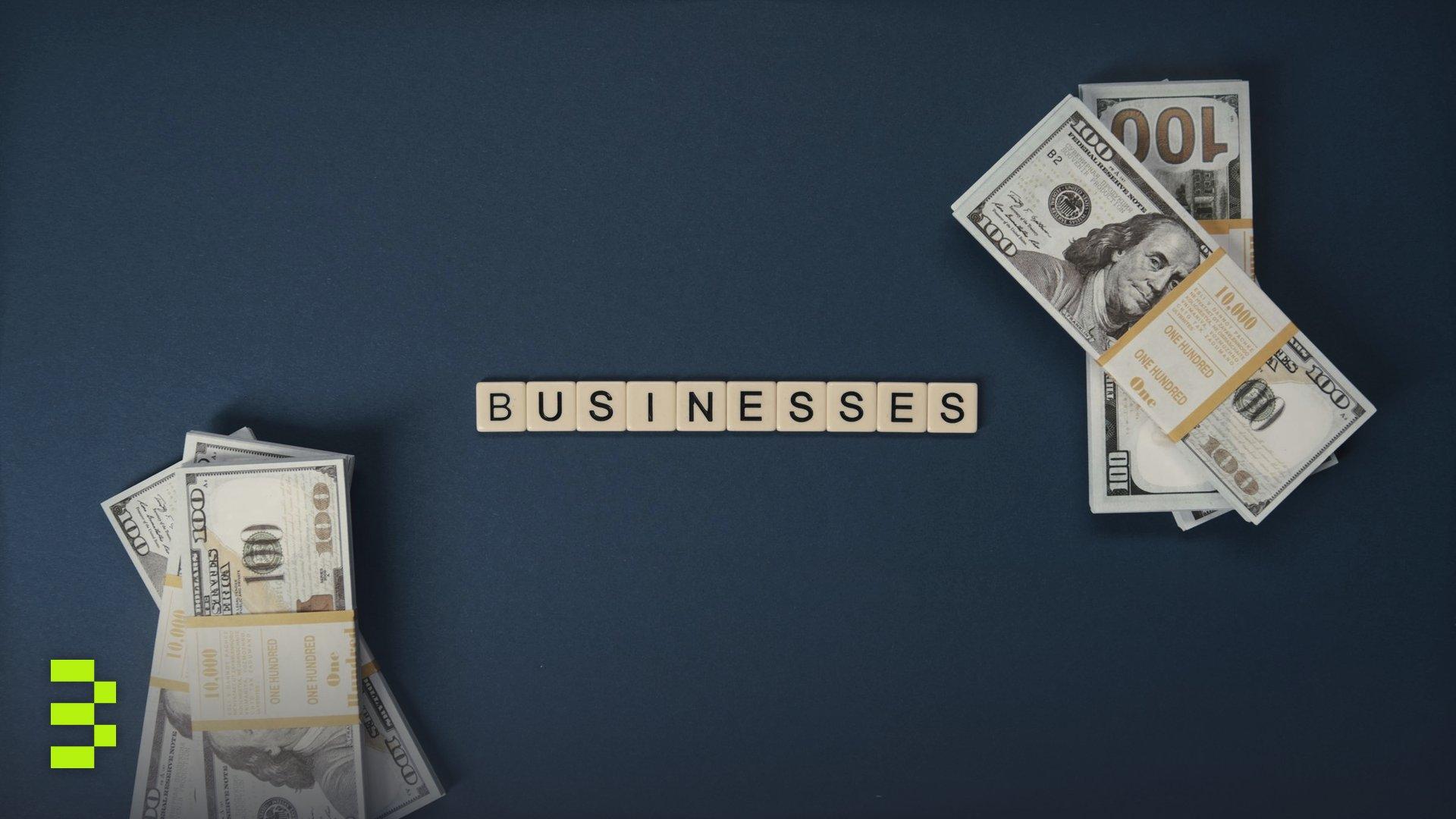 Top view of dollar bills and 'businesses' letter tiles.
