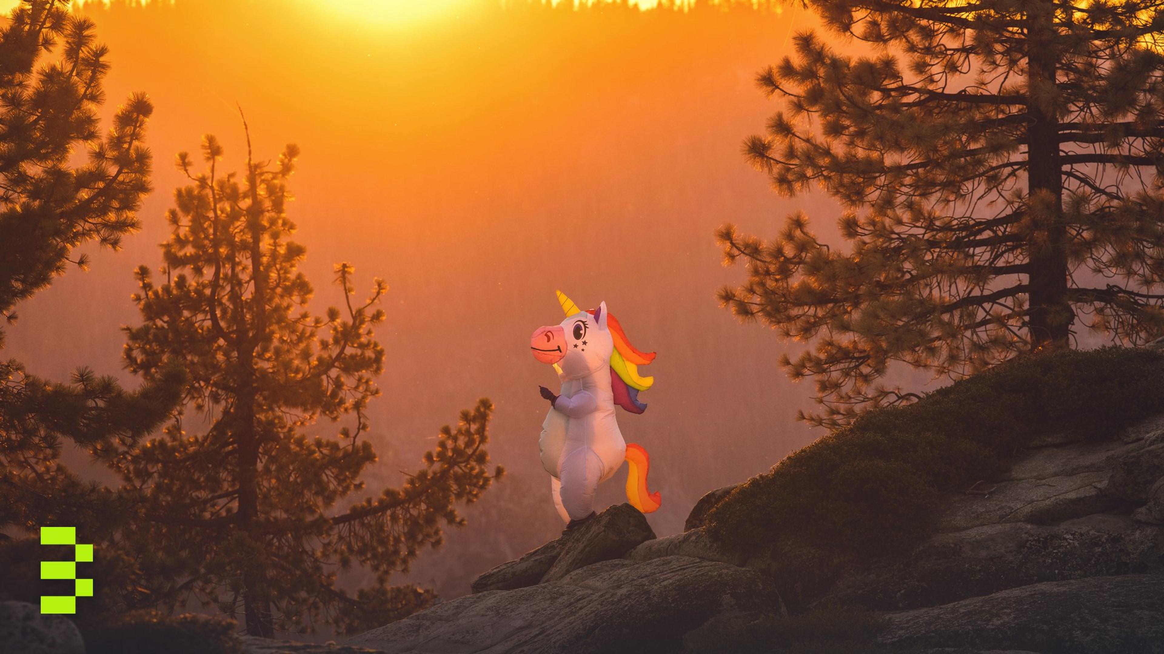 A unicorn figure on rocks among trees at sunset.