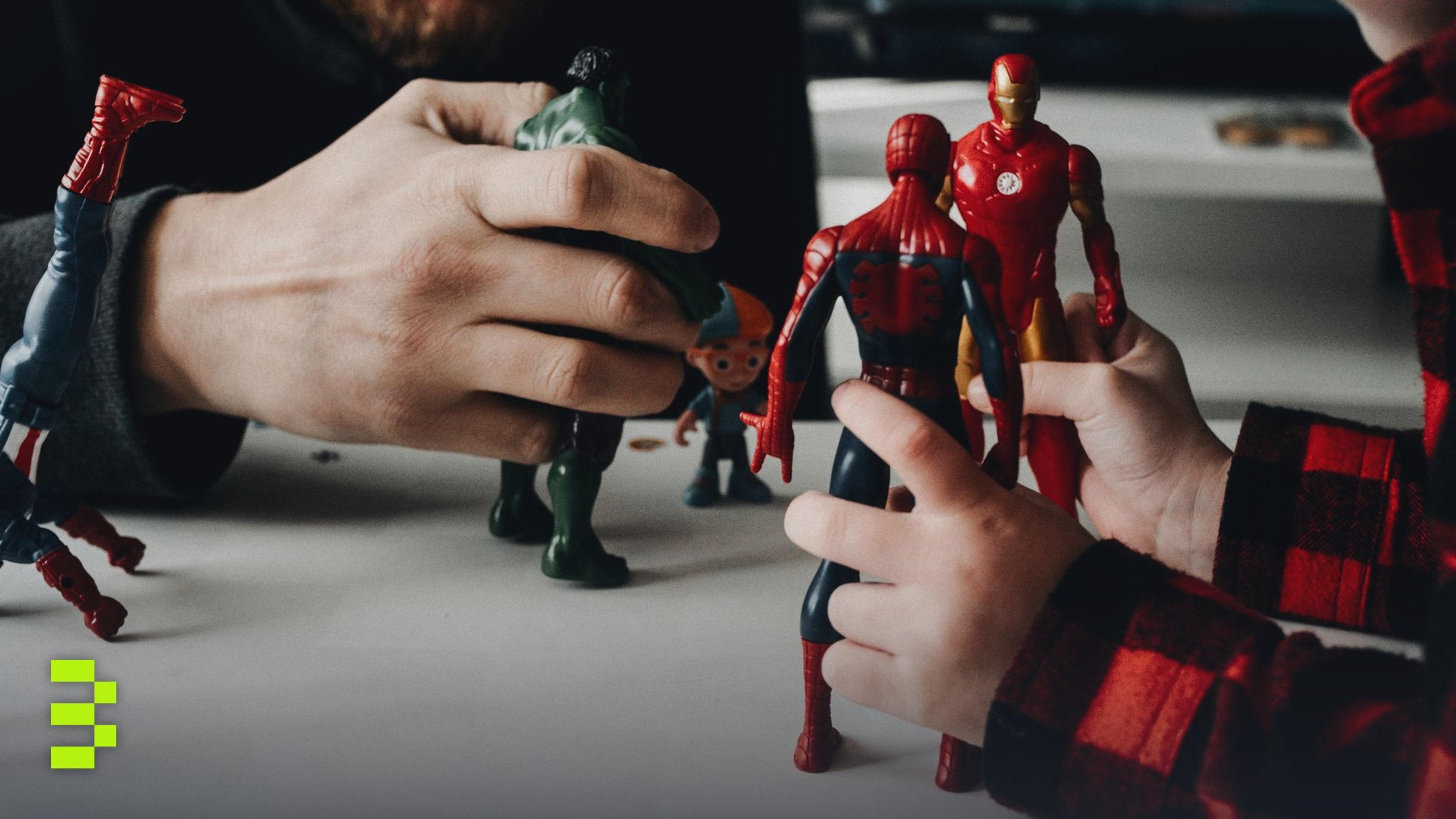A father and son bond while playing with superhero action figures indoors.