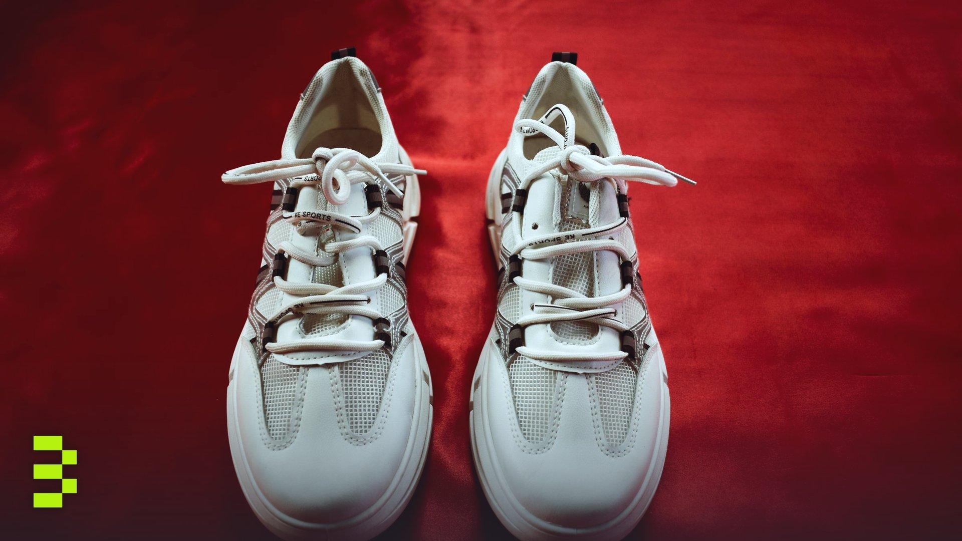 Top view of white sneakers on a red background.