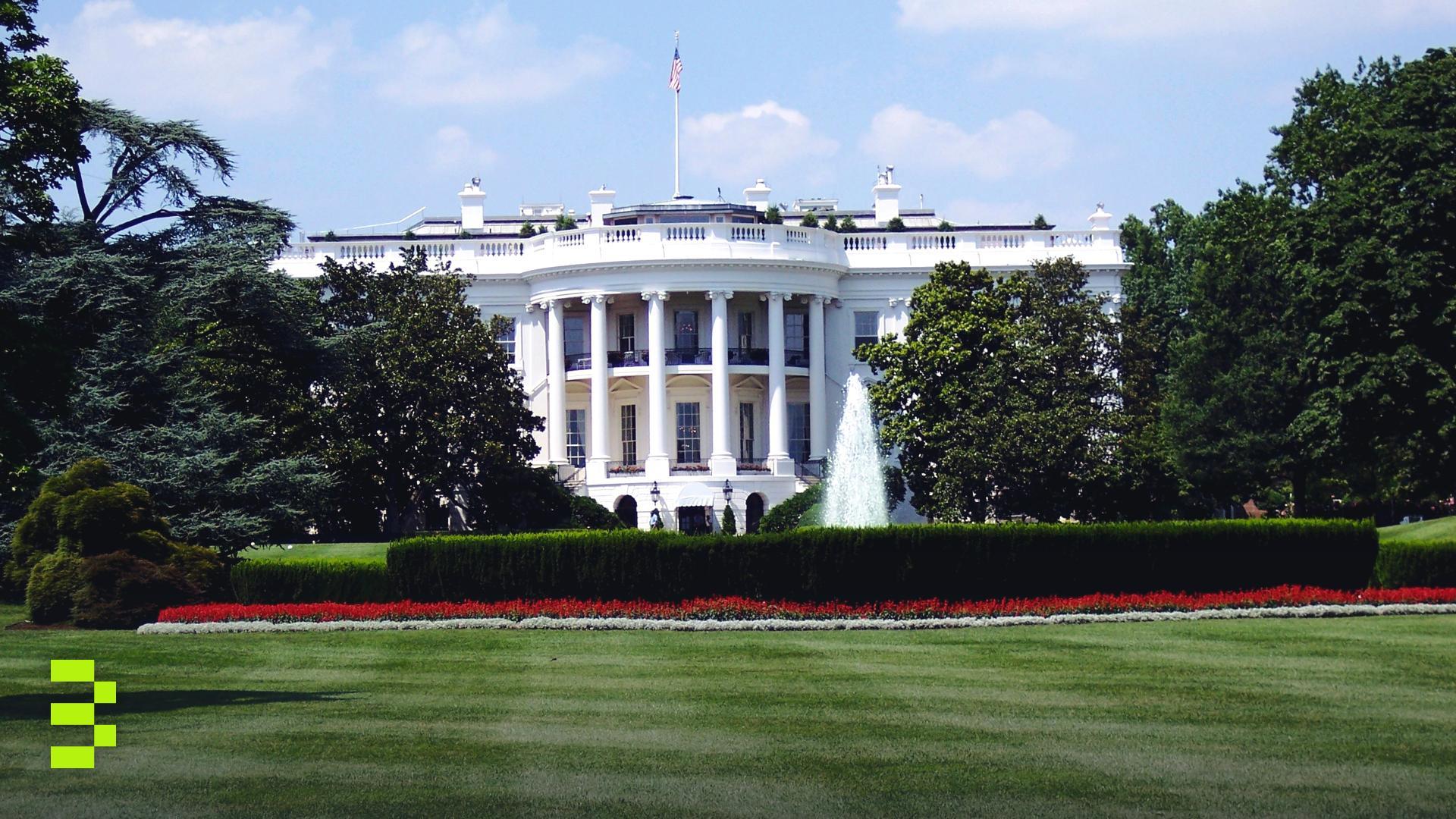 Iconic view of the White House with lush gardens and a central fountain on a sunny day.