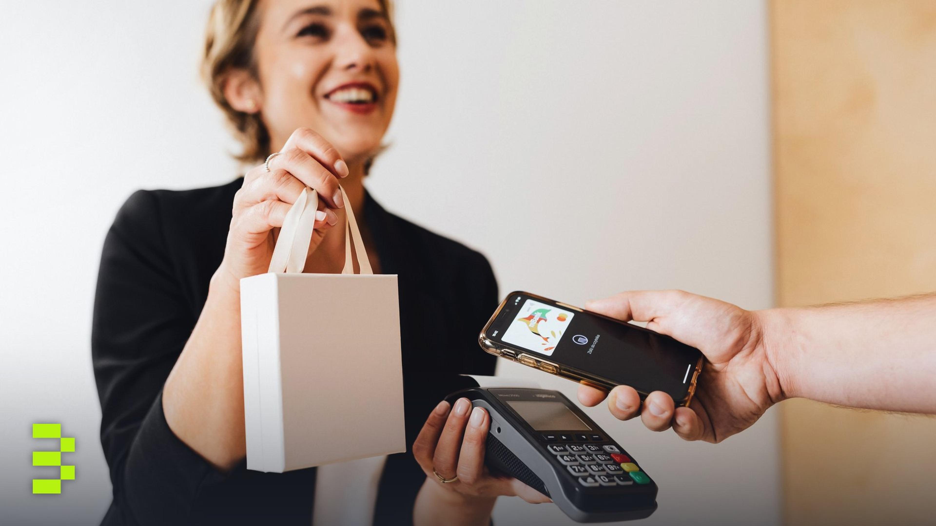 Smiling cashier handles a purchase with a contactless mobile payment in a modern shop.