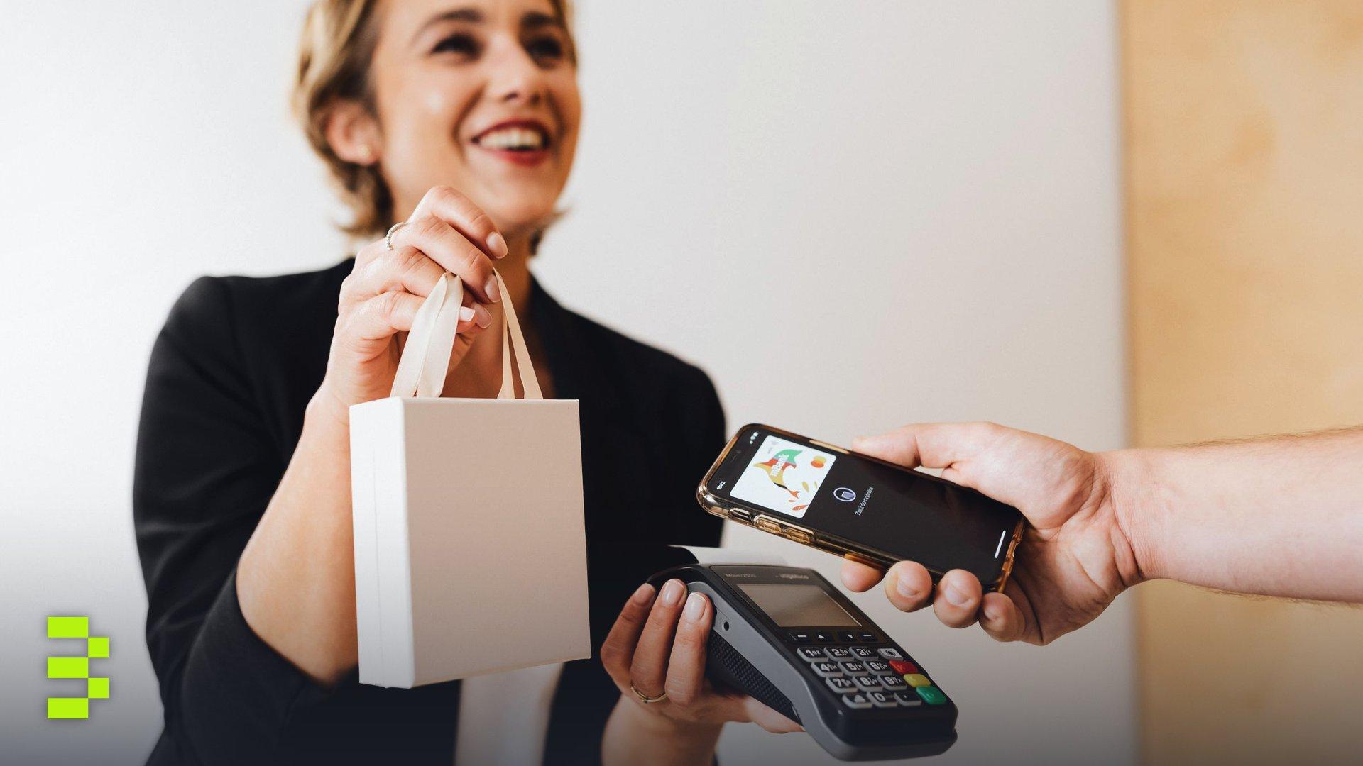 Smiling cashier handles a purchase with a contactless mobile payment in a modern shop.