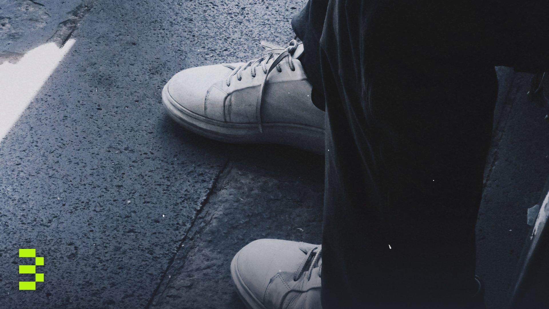 Close-up of white sneakers on a city street.