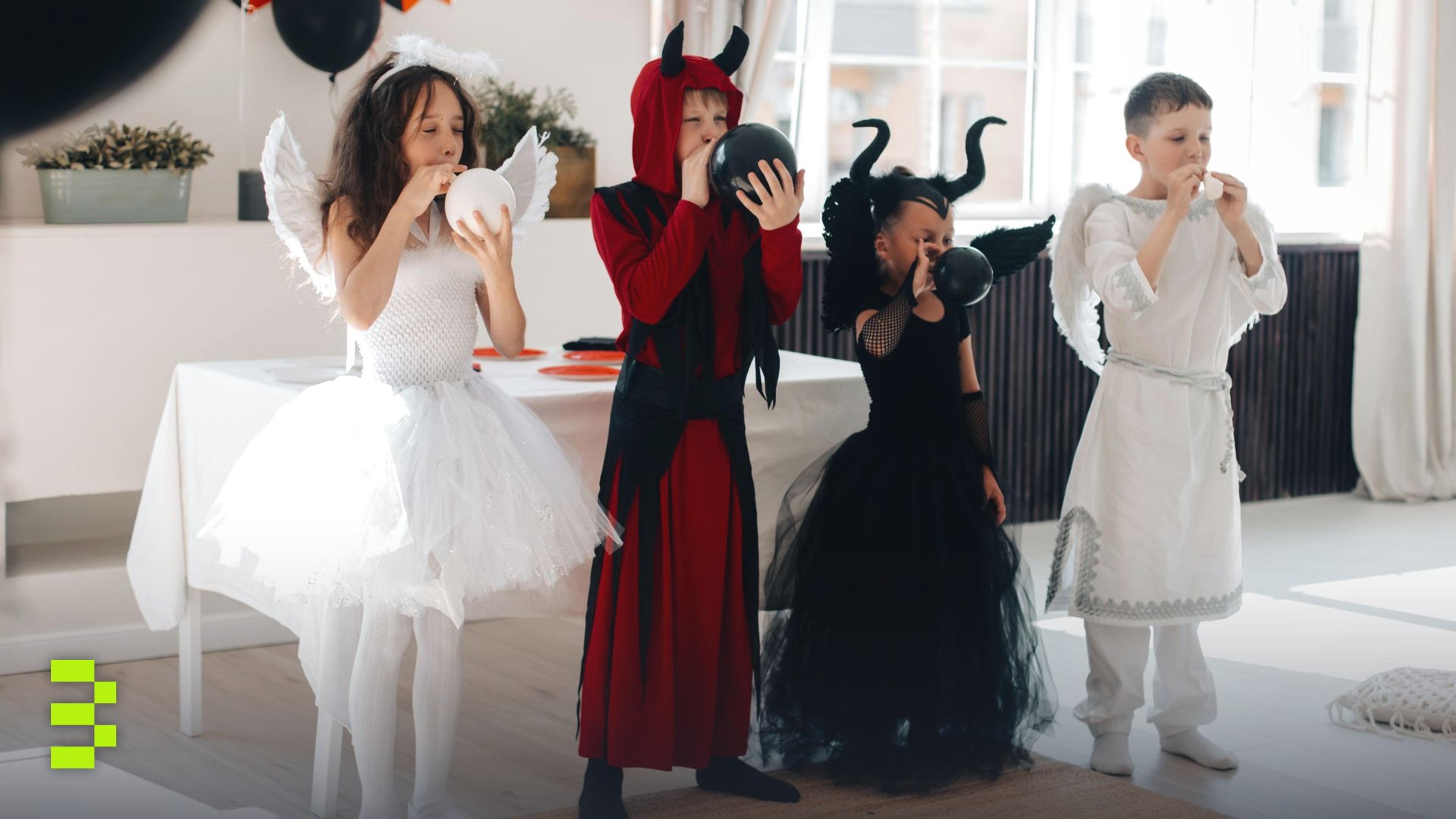 Children in festive Halloween costumes blowing up balloons at a party indoors.