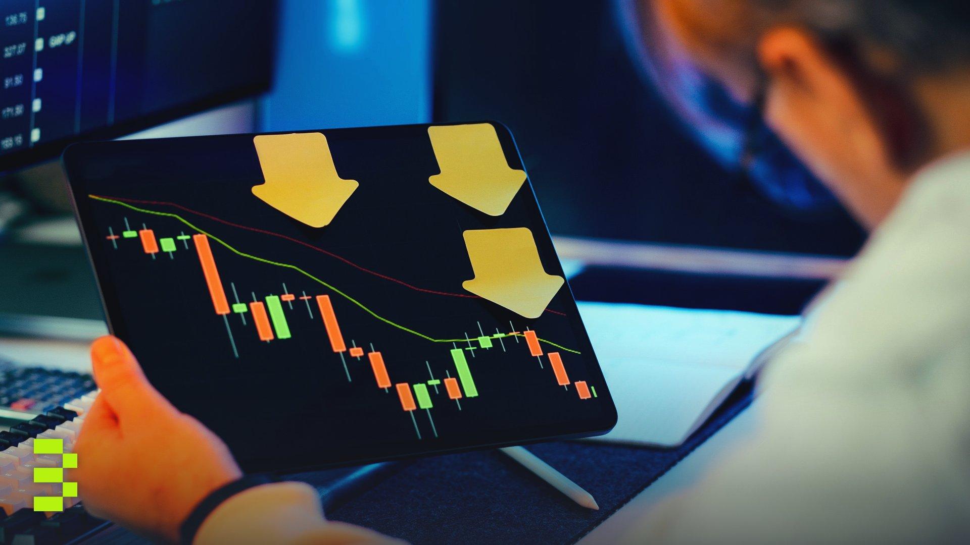 A businessman reviewing a falling stock market chart on a tablet.