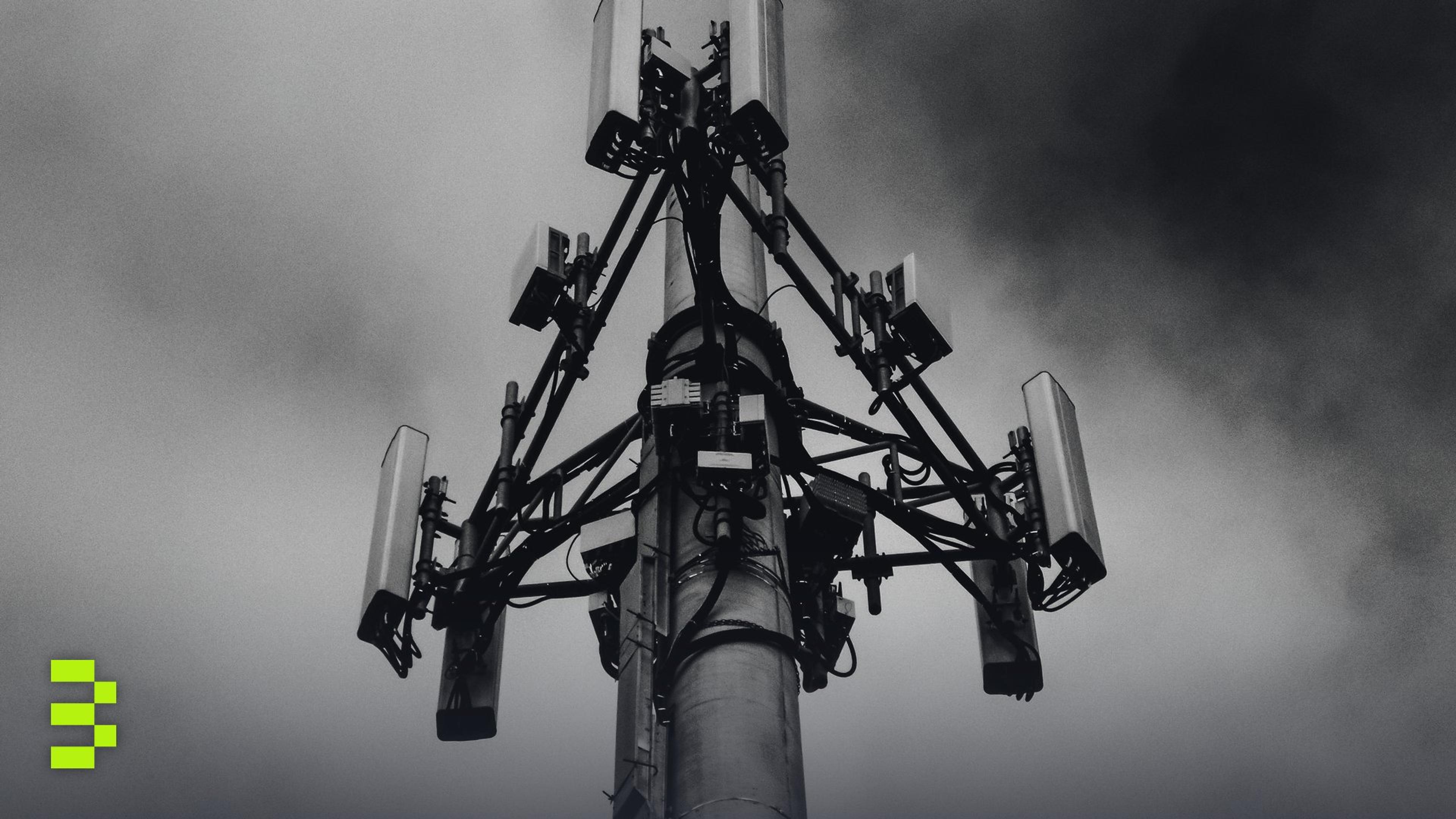 A dramatic monochrome image of a cell tower against a cloudy sky.