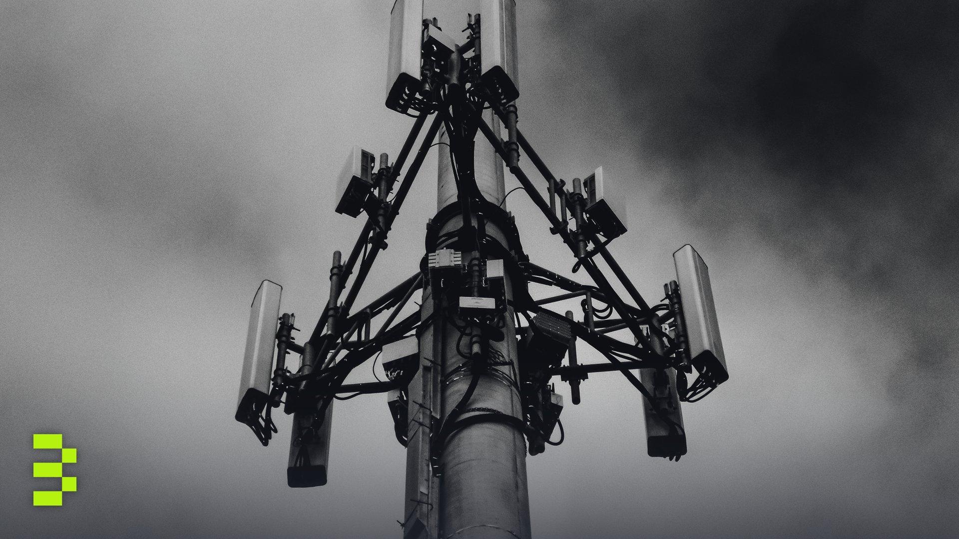 A dramatic monochrome image of a cell tower against a cloudy sky.