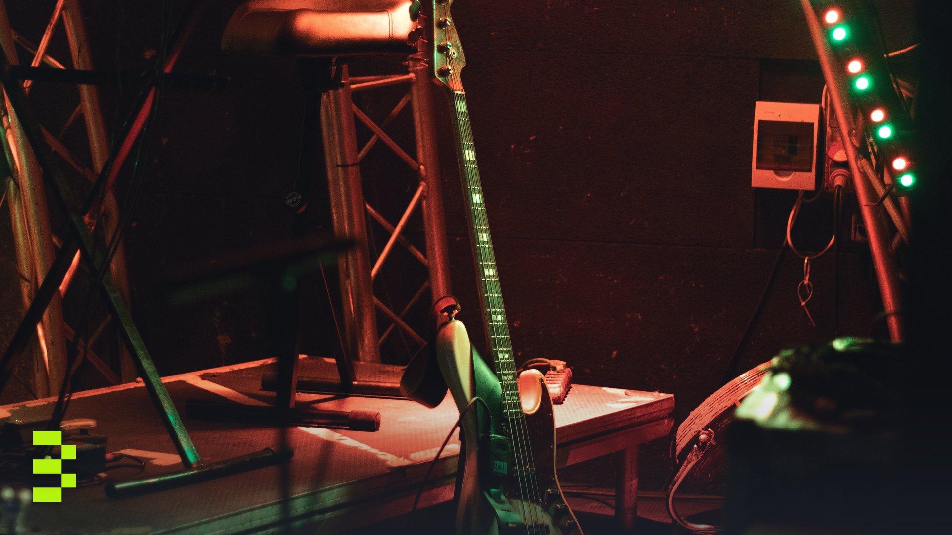 An atmospheric stage with a bass guitar and vibrant strip lights, ready for a live performance.