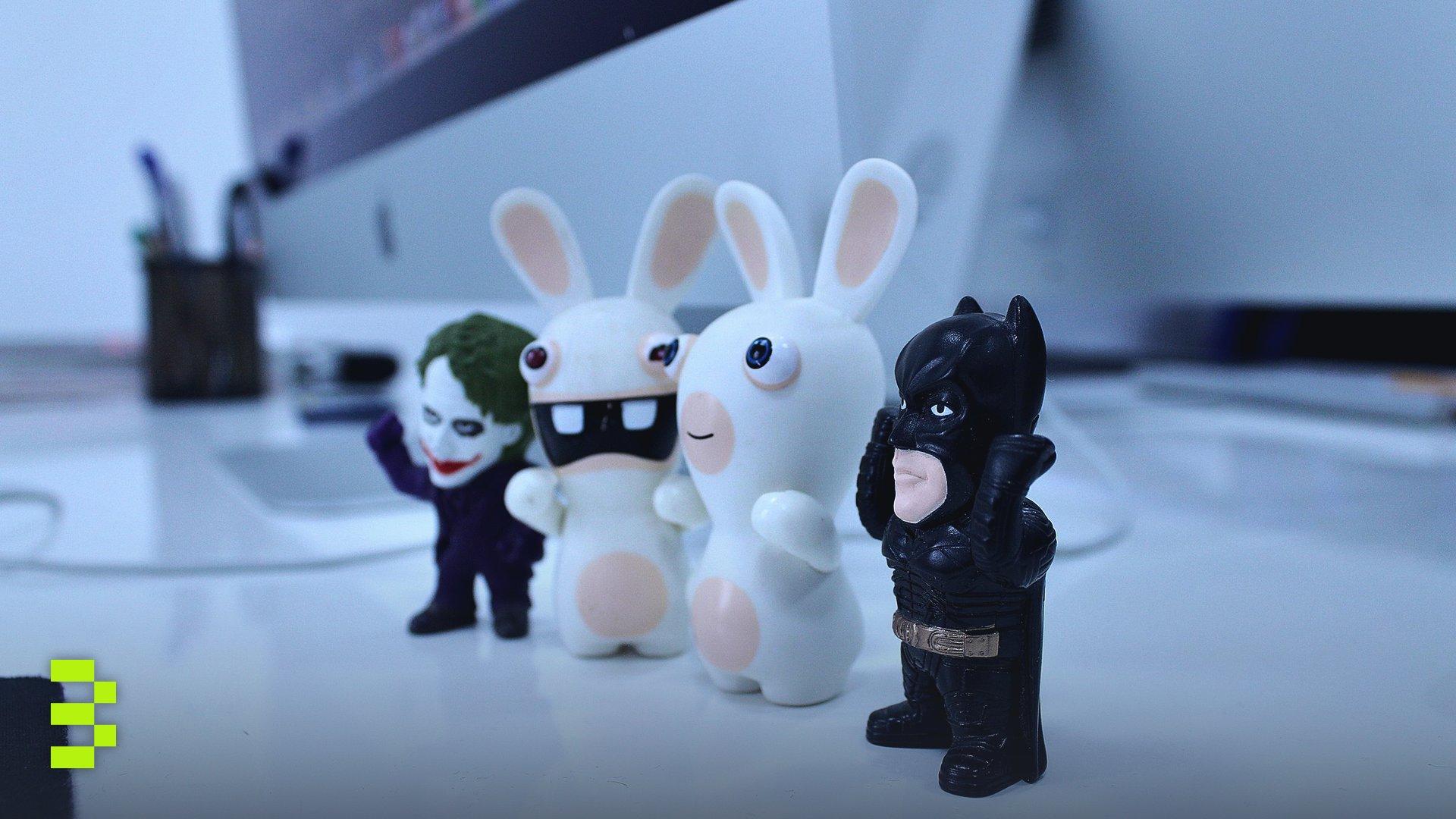 Close-up of various cartoon figurines on a modern desk setting.