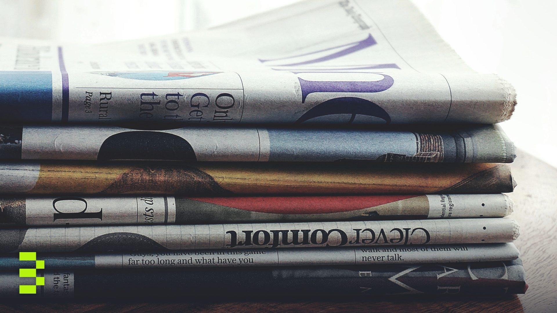 A stack of folded newspapers placed on a wooden table.