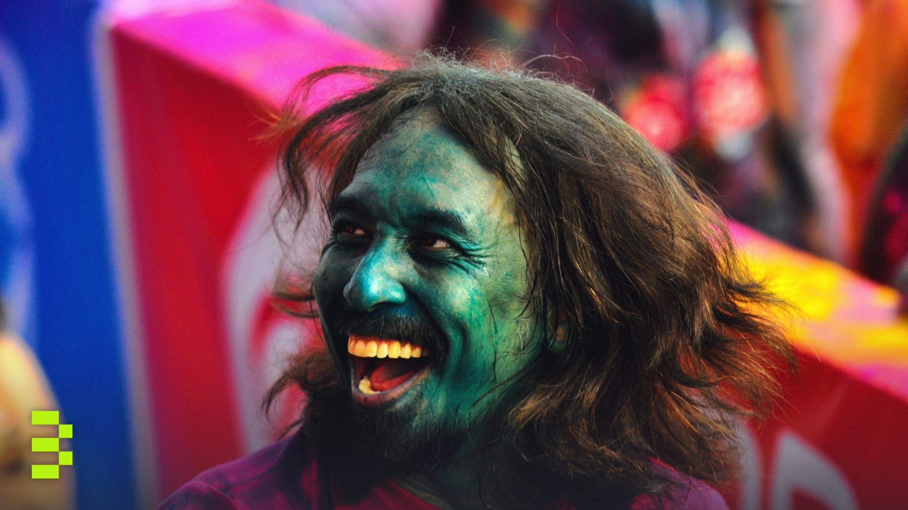 A man with a painted face laughing during Holi, the festival of colors.