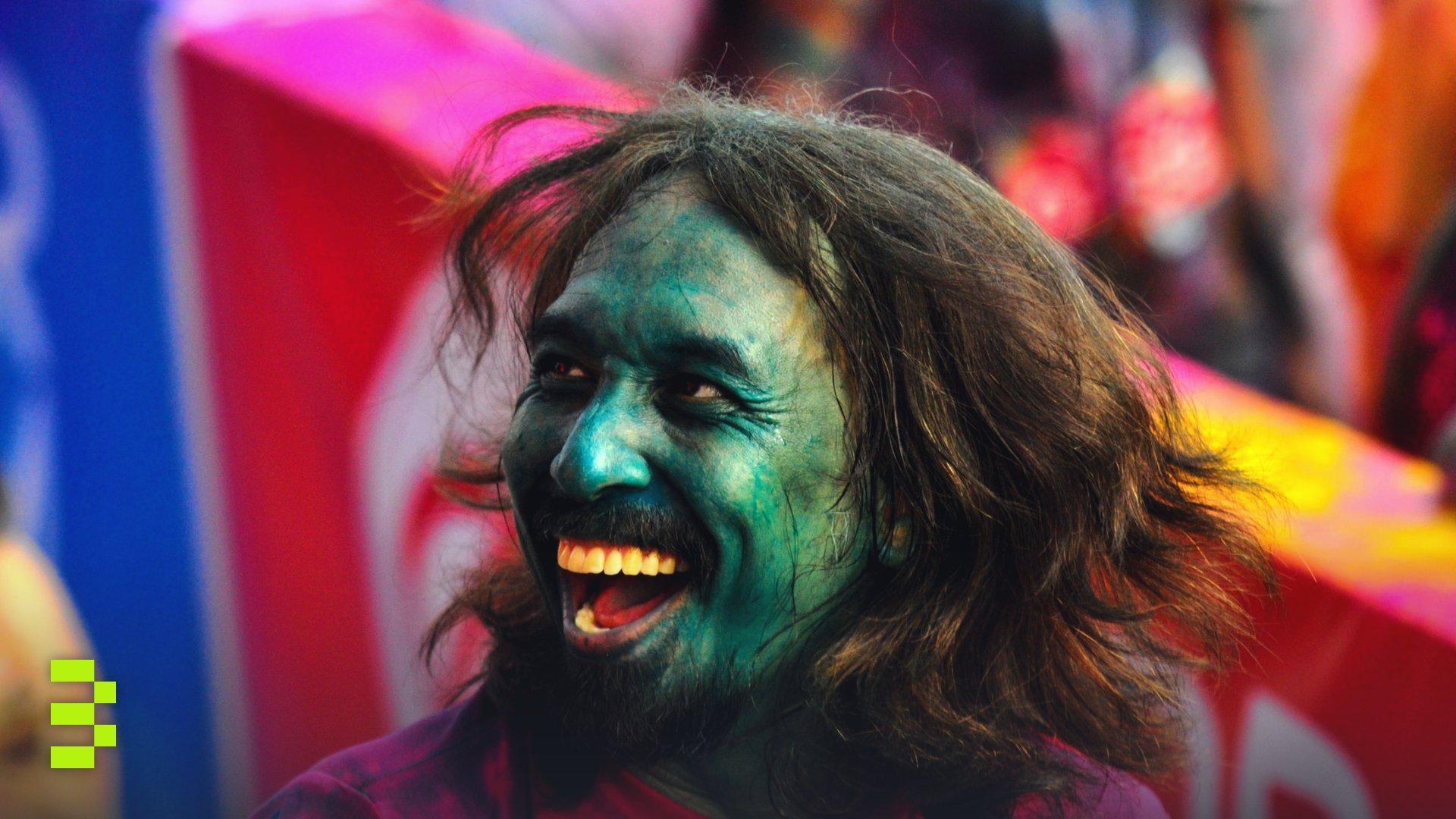 A man with a painted face laughing during Holi, the festival of colors.