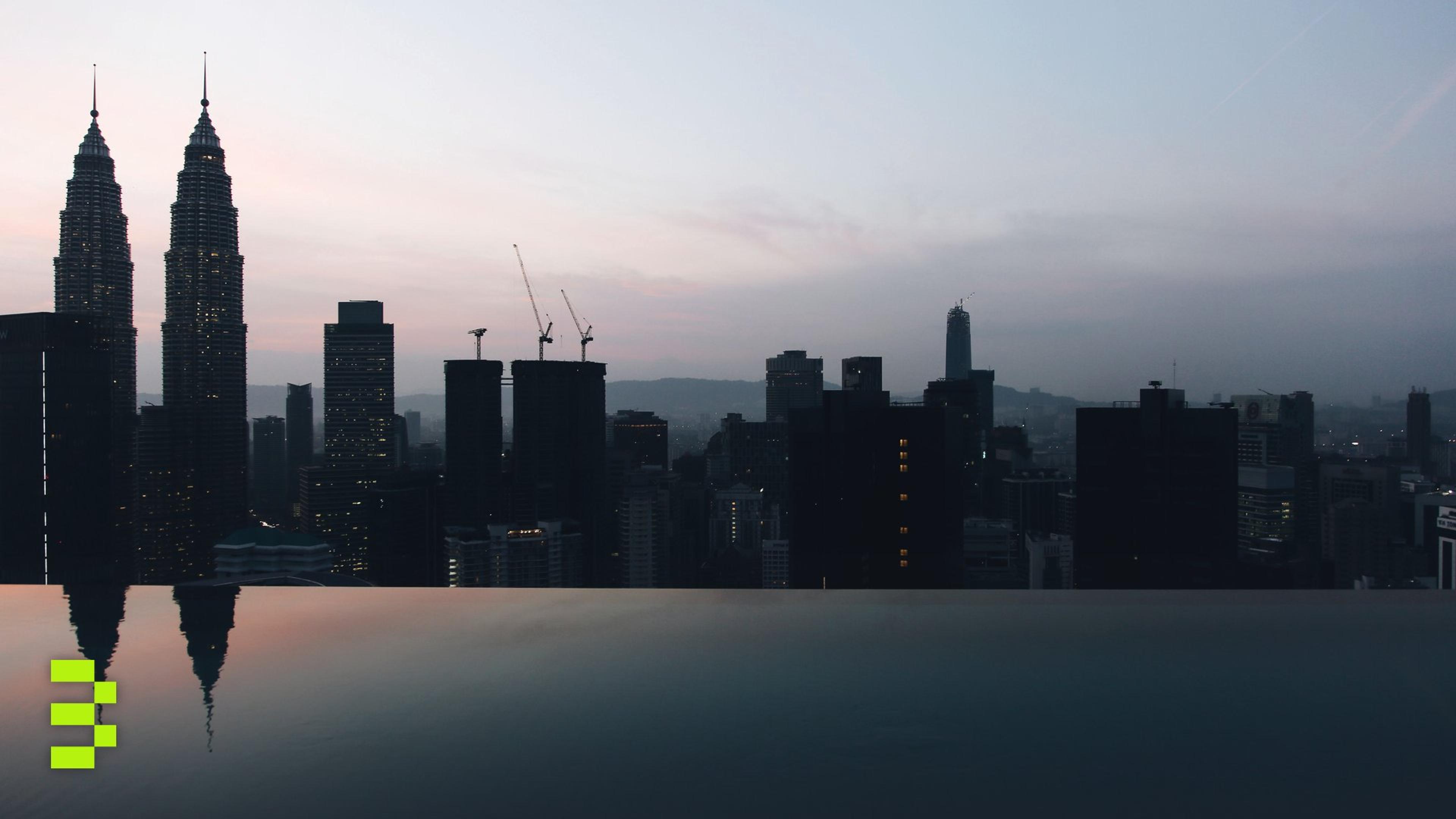 Twilight view of the Kuala Lumpur skyline and the Petronas Twin Towers reflected in an infinity pool.