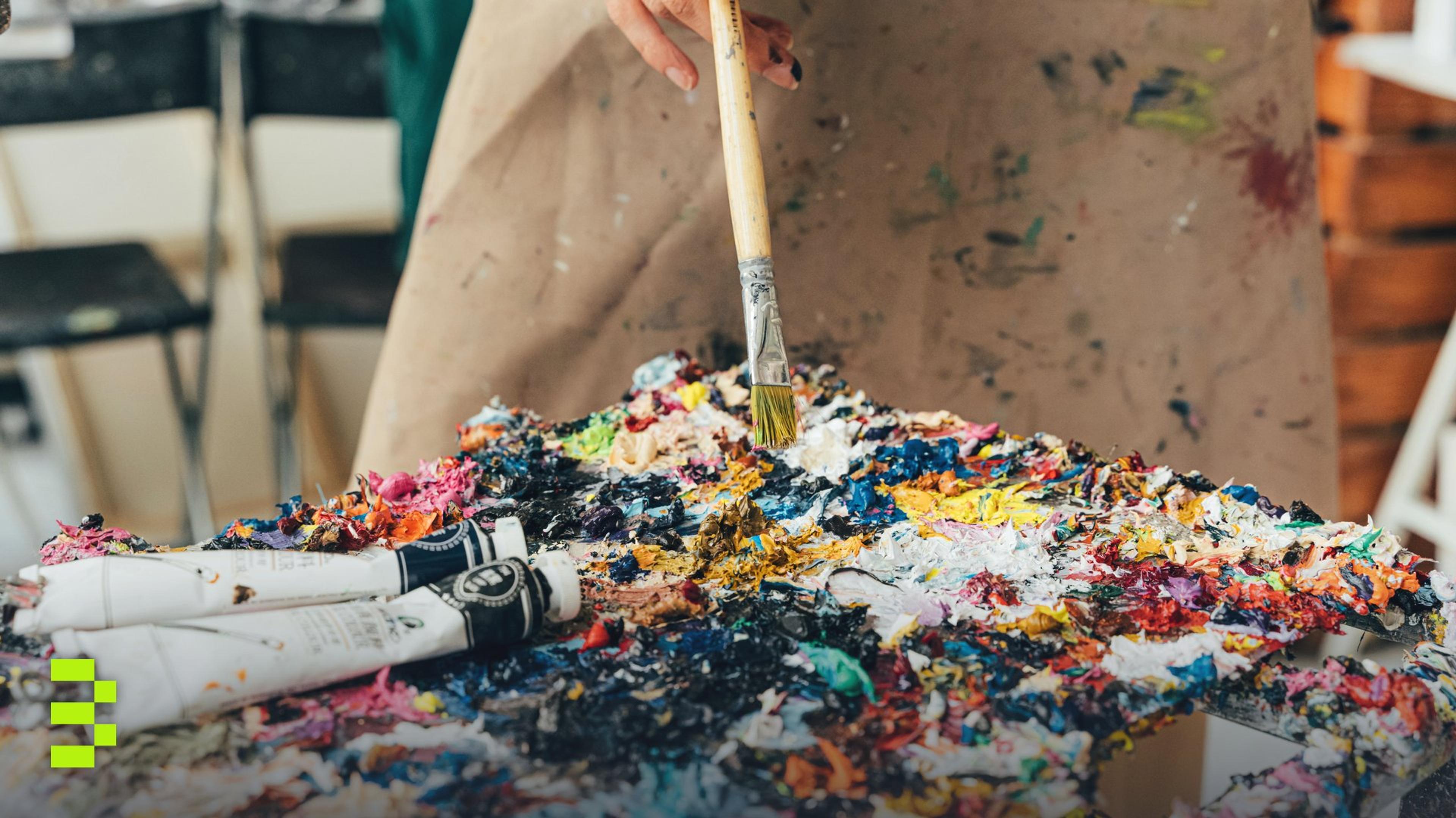 Vibrant paint palette with brush and tubes in an artist's studio setting.