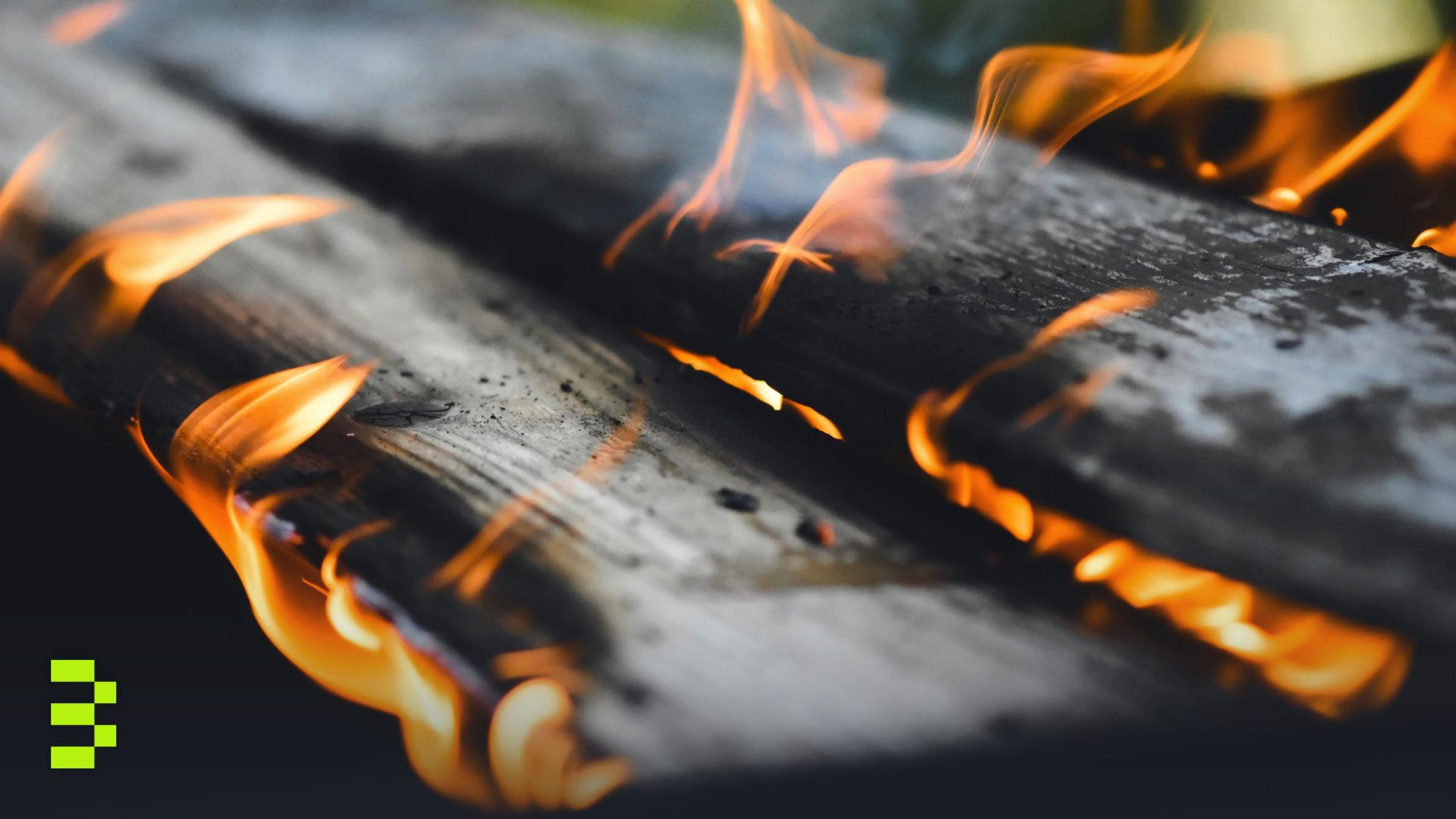Vivid flames engulf wooden planks in an outdoor fire setting.
