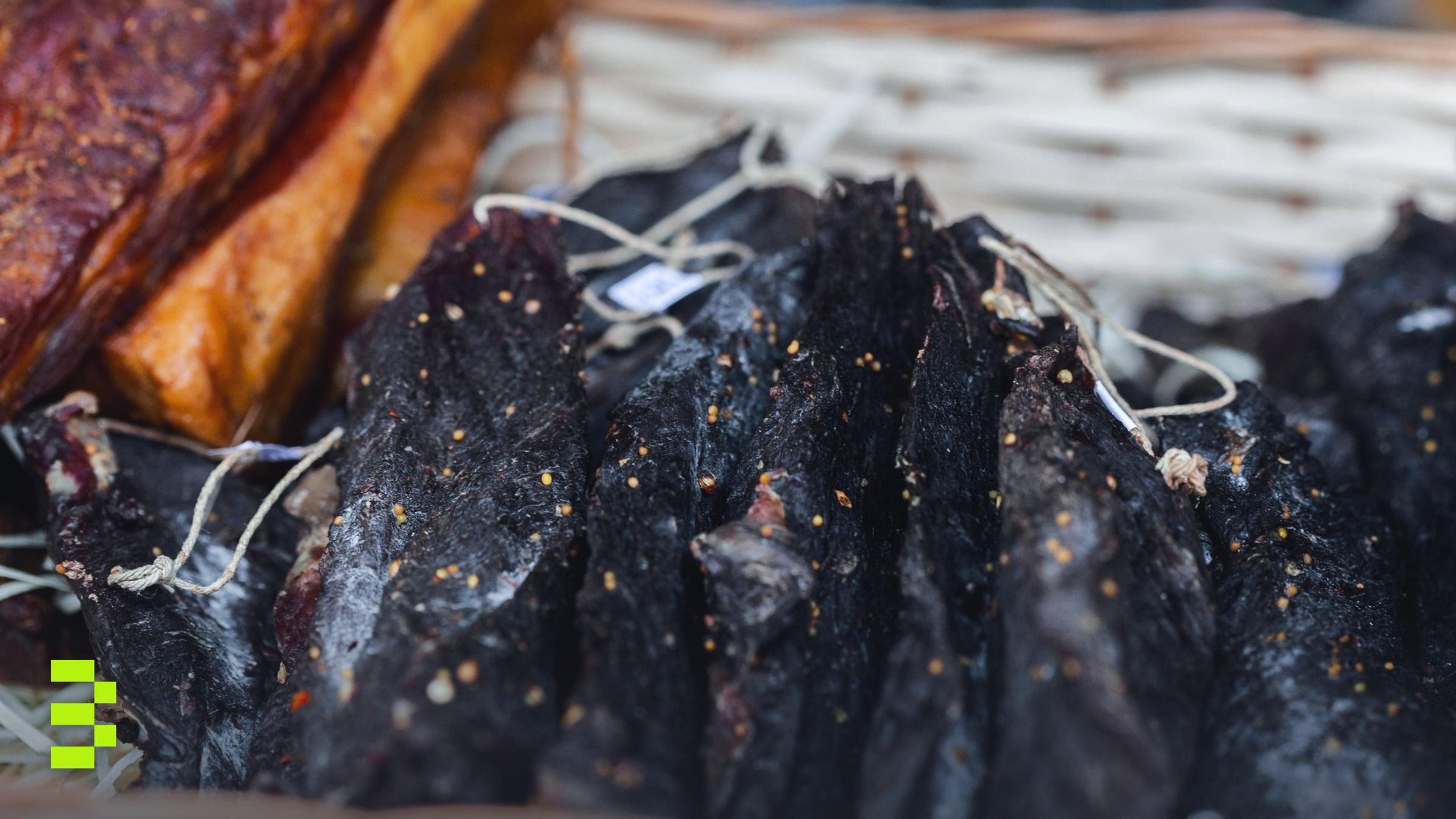 A close-up view of dried, seasoned meat slices displayed in a wicker basket.