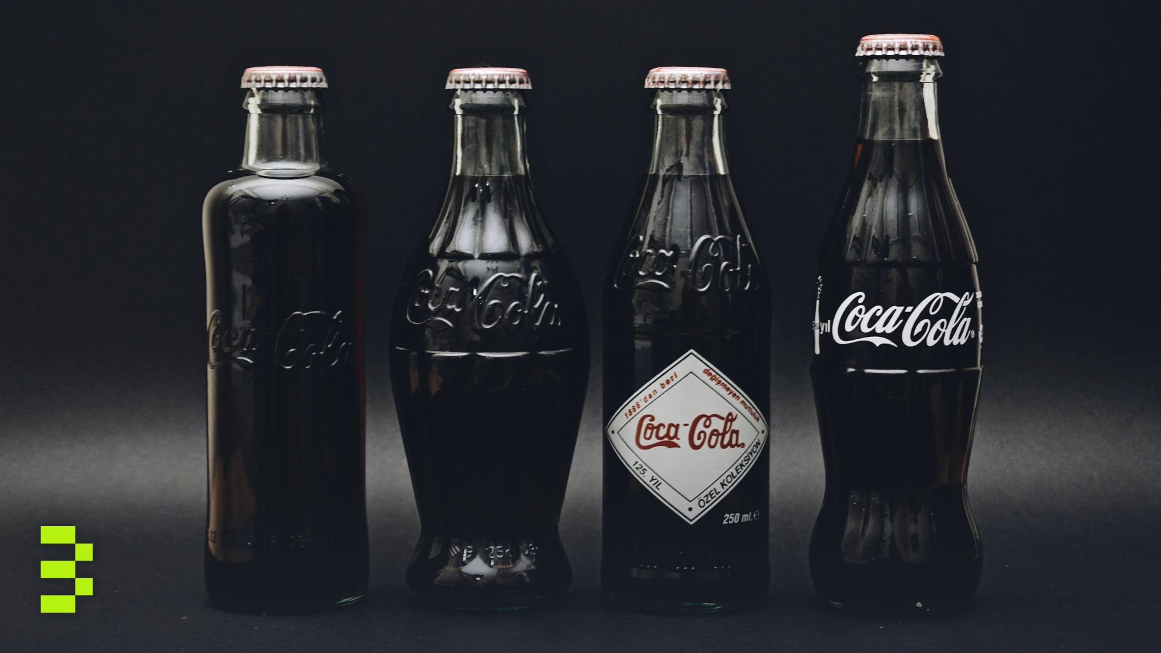 Four classic Coca-Cola glass bottles on a dark background.
