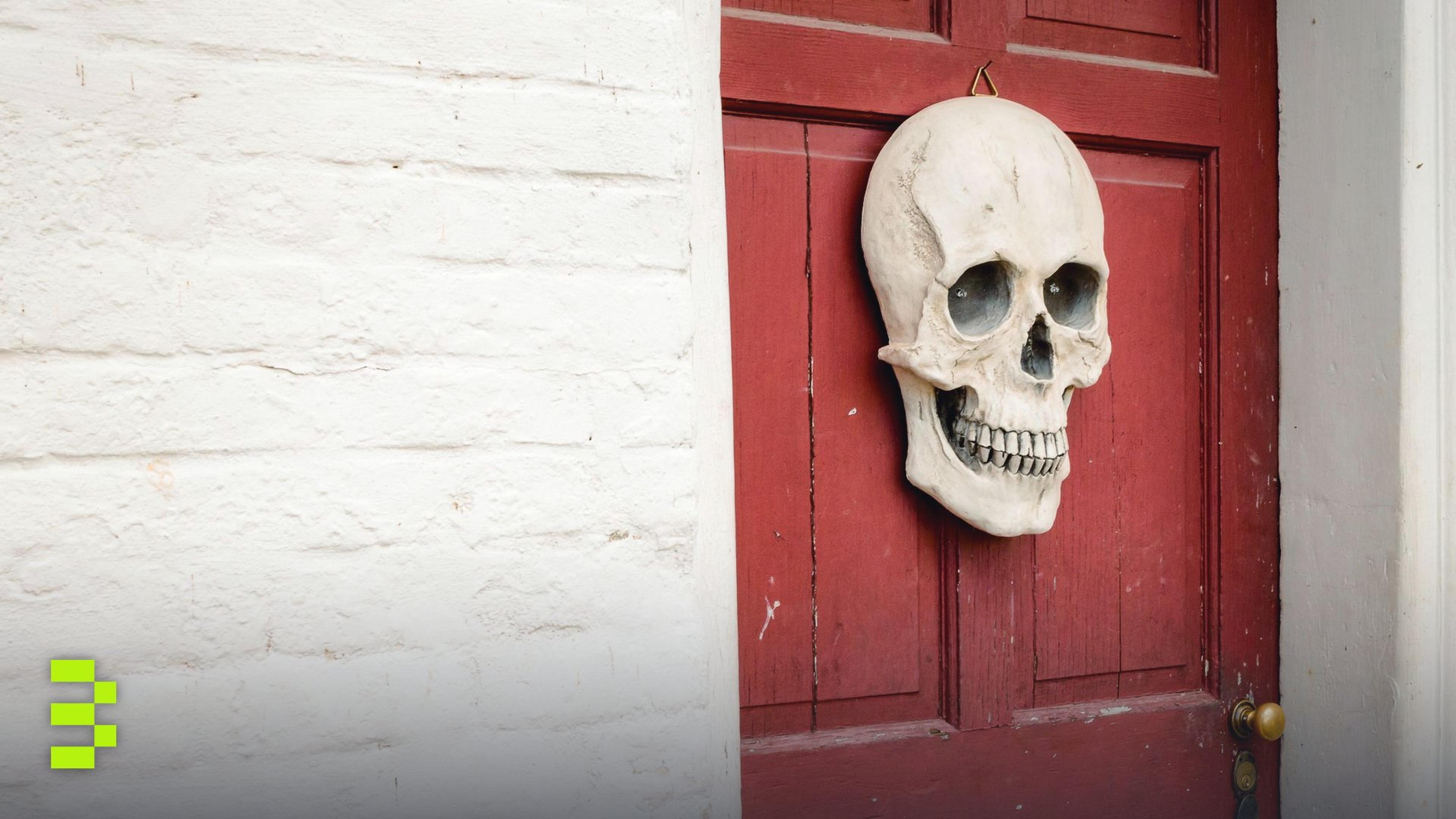 A skull decoration hanging on a red door.