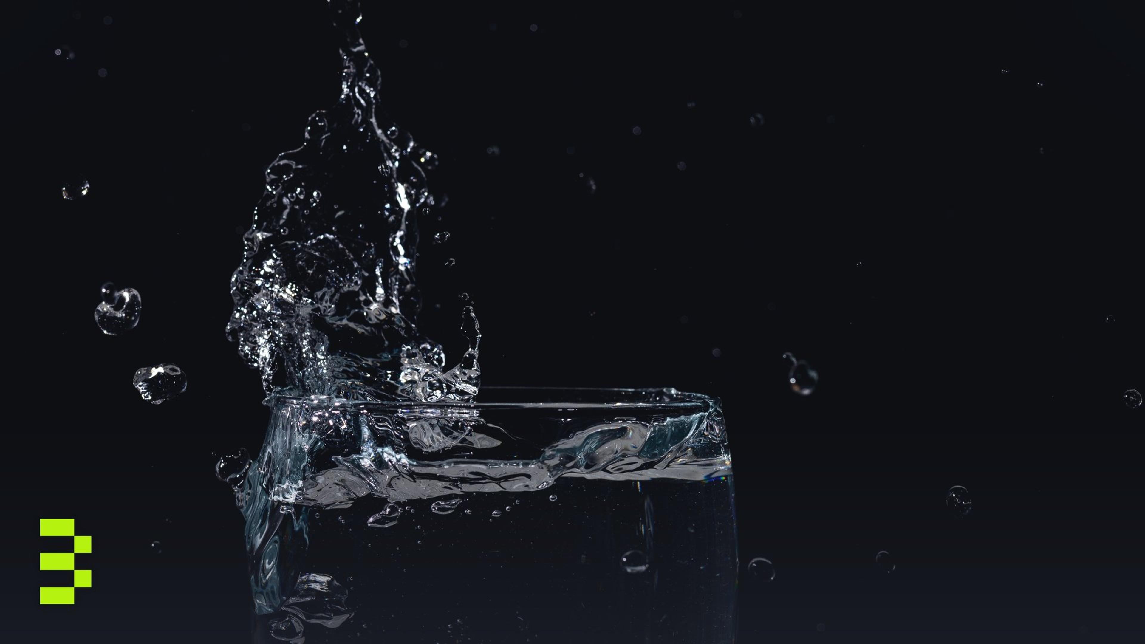 Close-up of water splashing in a glass against a black background.