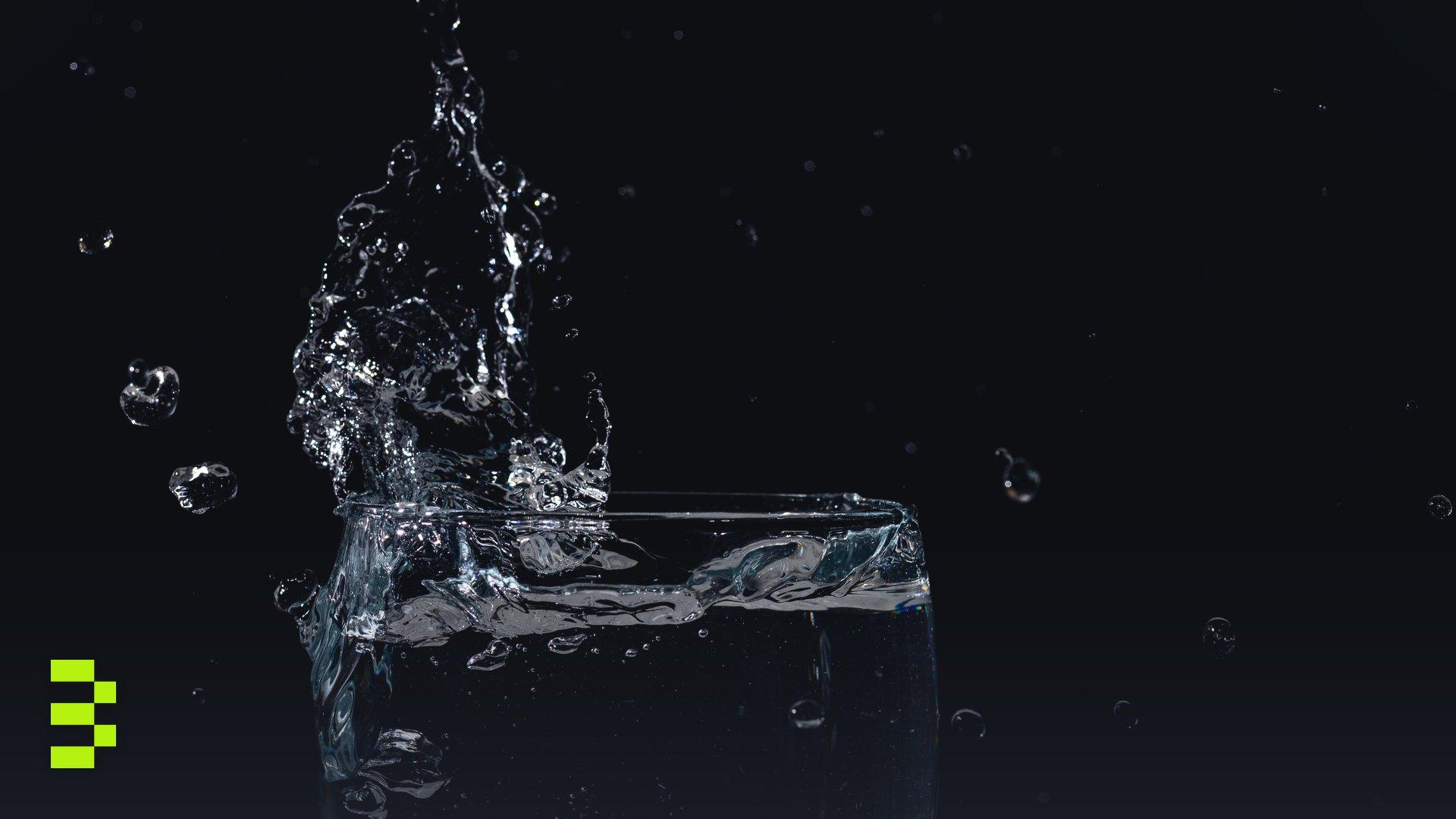 Close-up of water splashing in a glass against a black background.