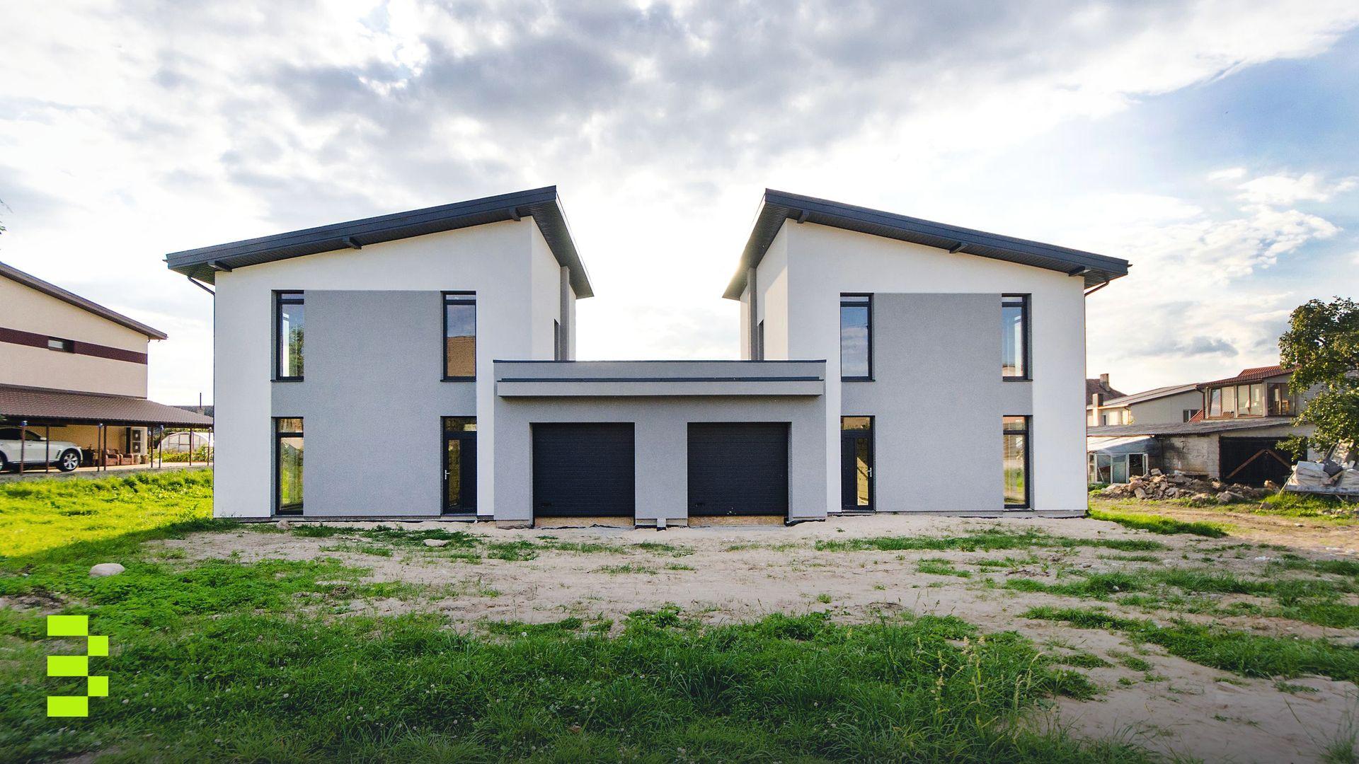 Front view of twin modern houses with a symmetrical architectural design under a cloudy sky.