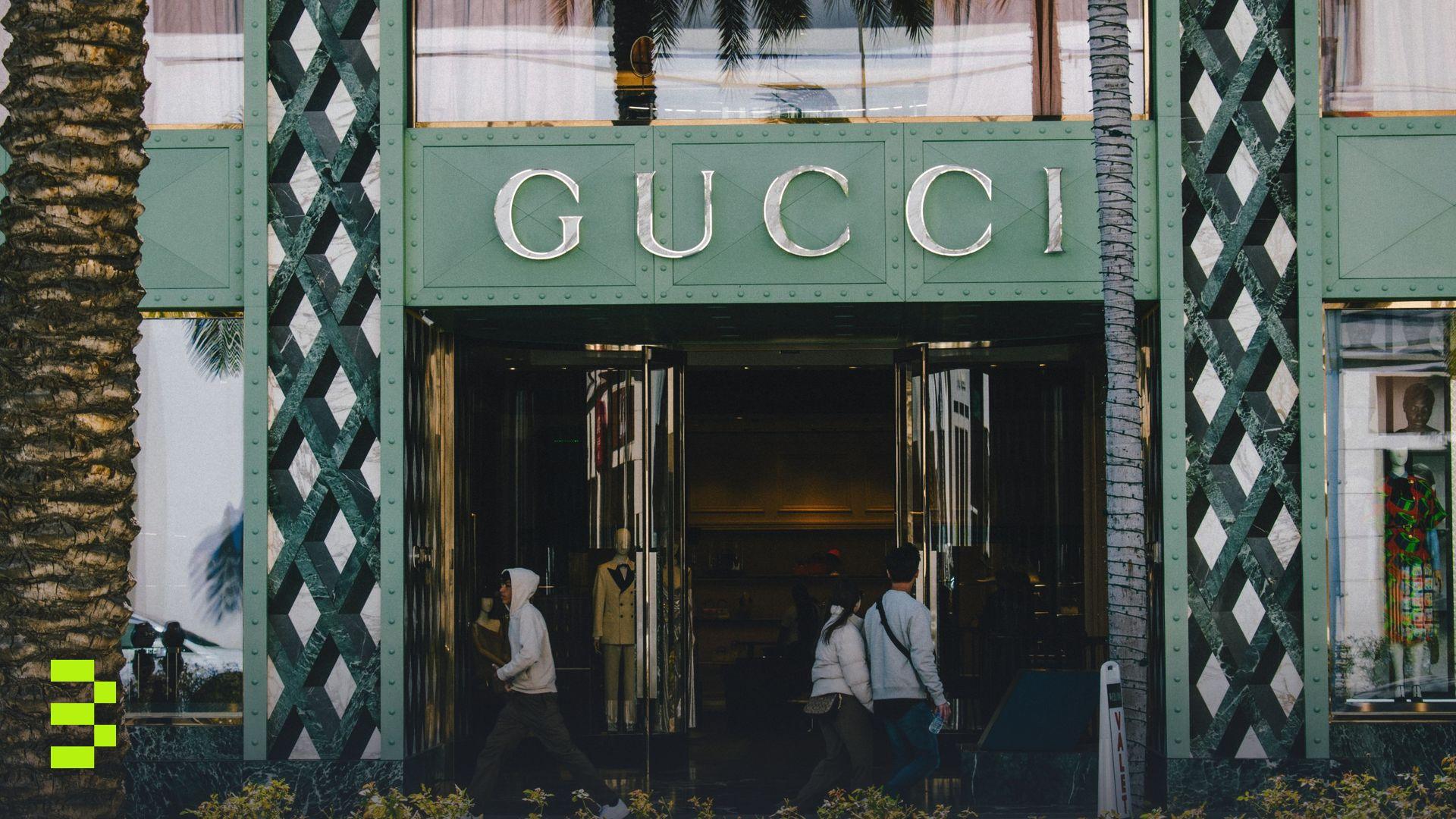 Gucci store facade with people passing by on a sunny day.