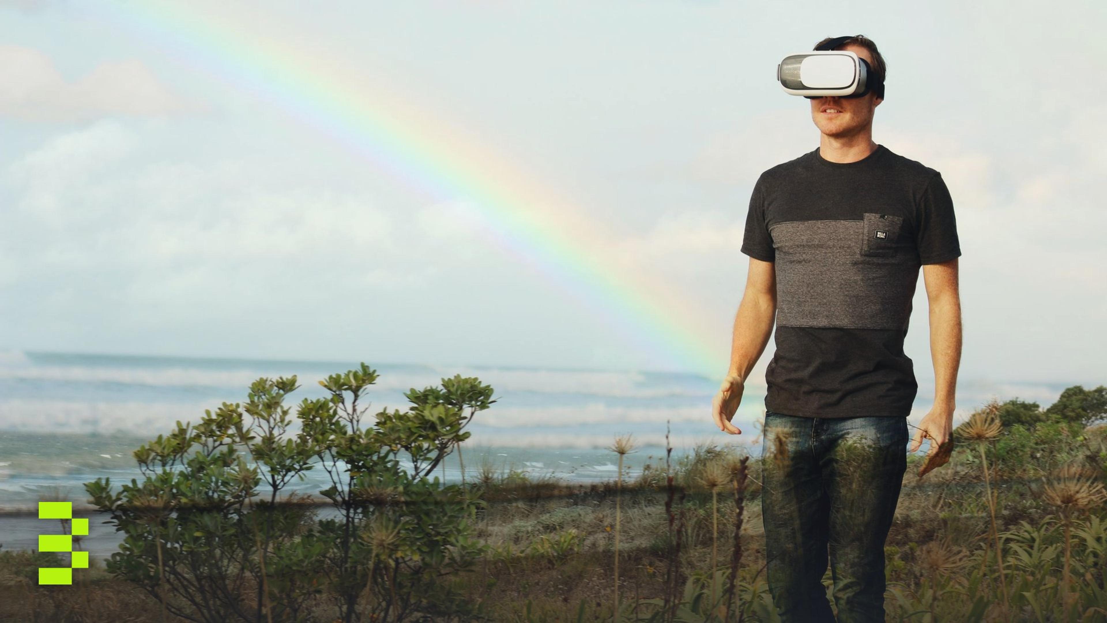 Man using VR headset walks in nature under a rainbow.