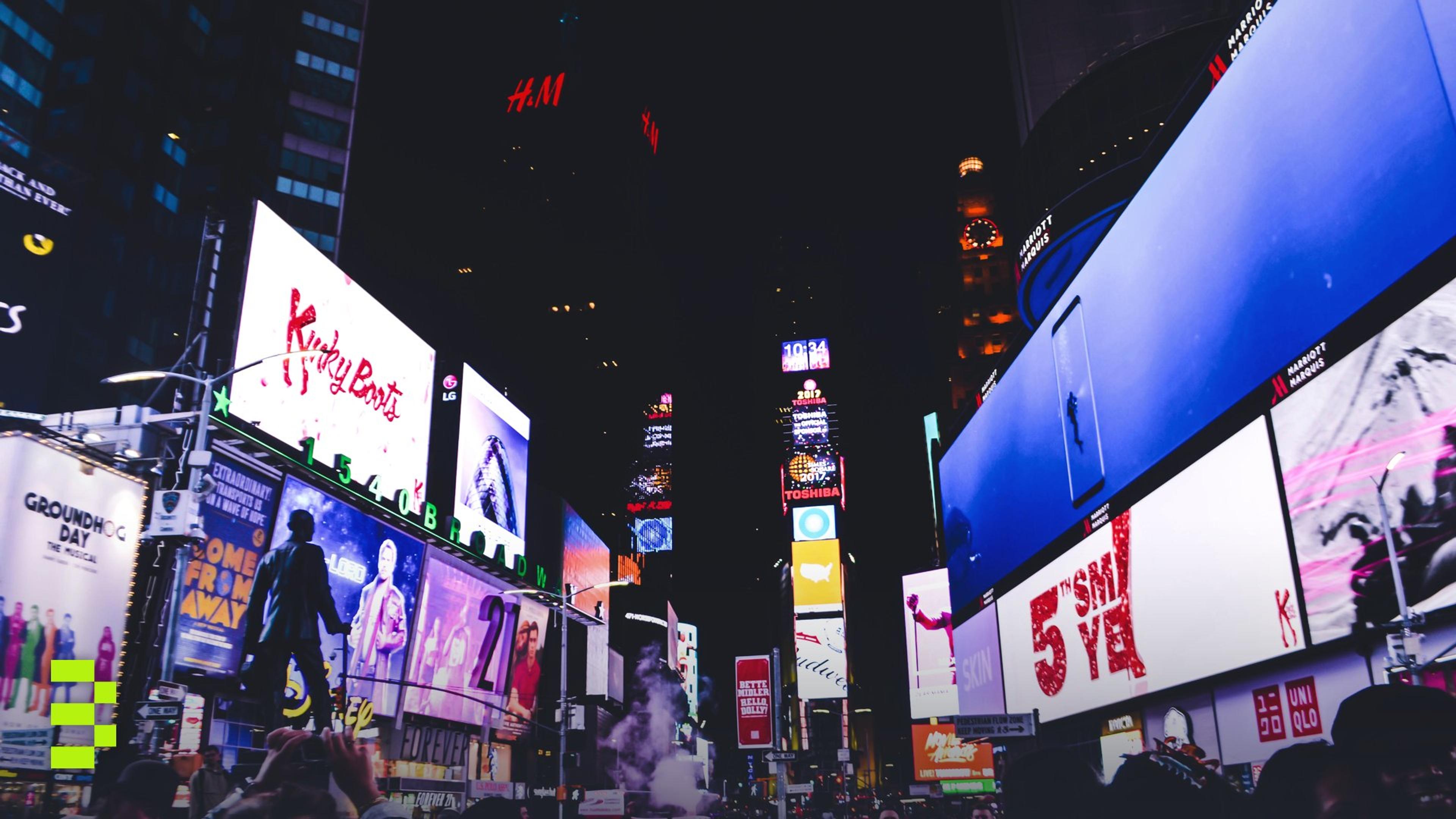 Bustling Times Square in New York City illuminated by bright digital billboards and a lively crowd at night.