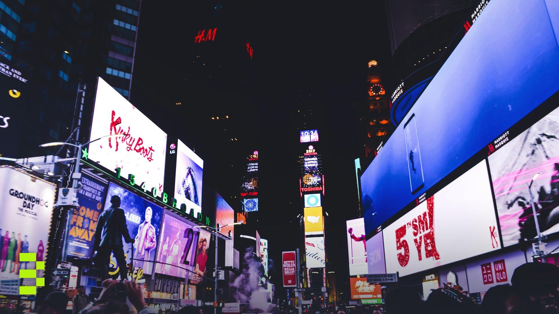Bustling Times Square in New York City illuminated by bright digital billboards and a lively crowd at night.