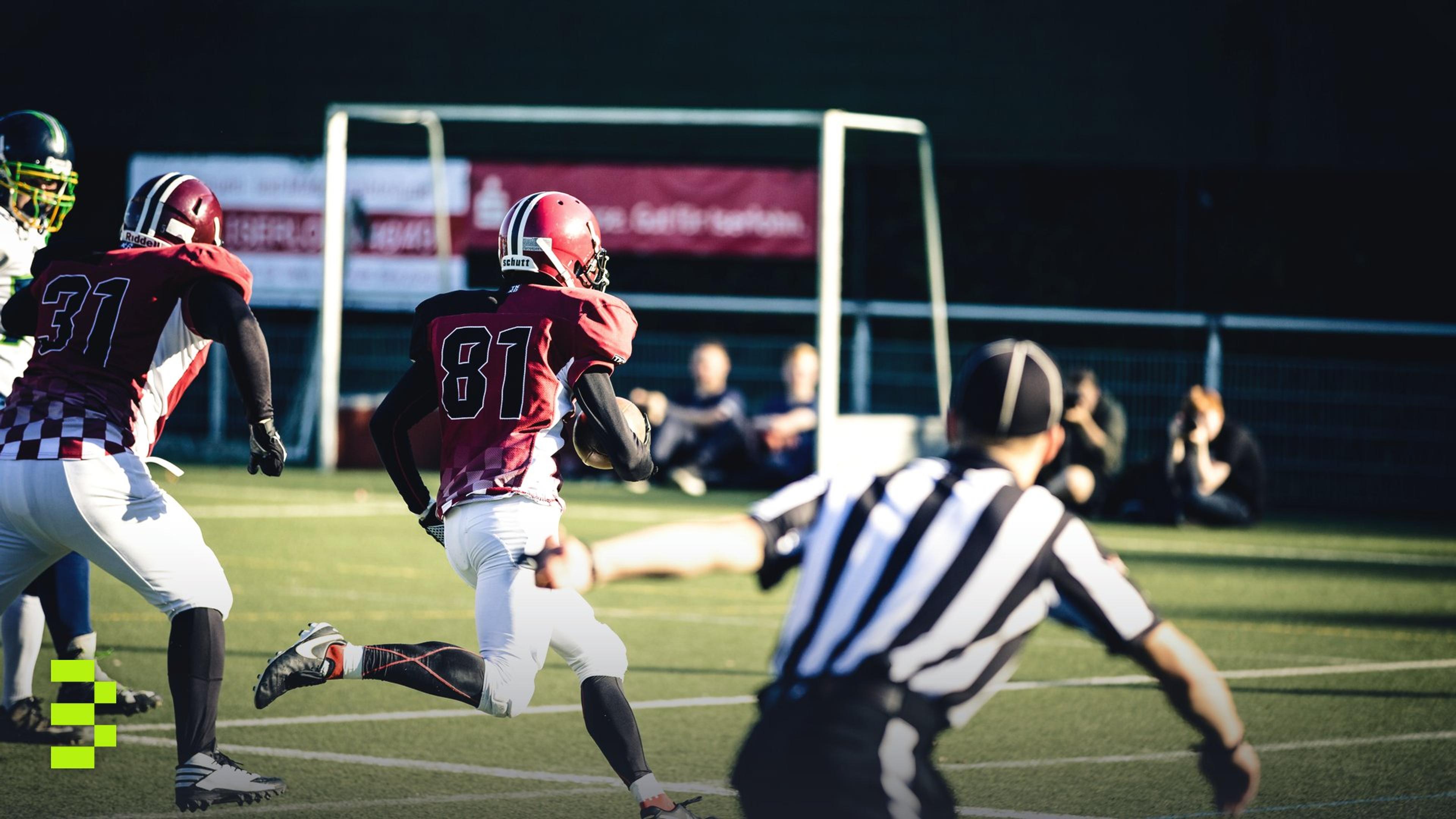 Intense action shot of American football players running on a field during a competitive game.