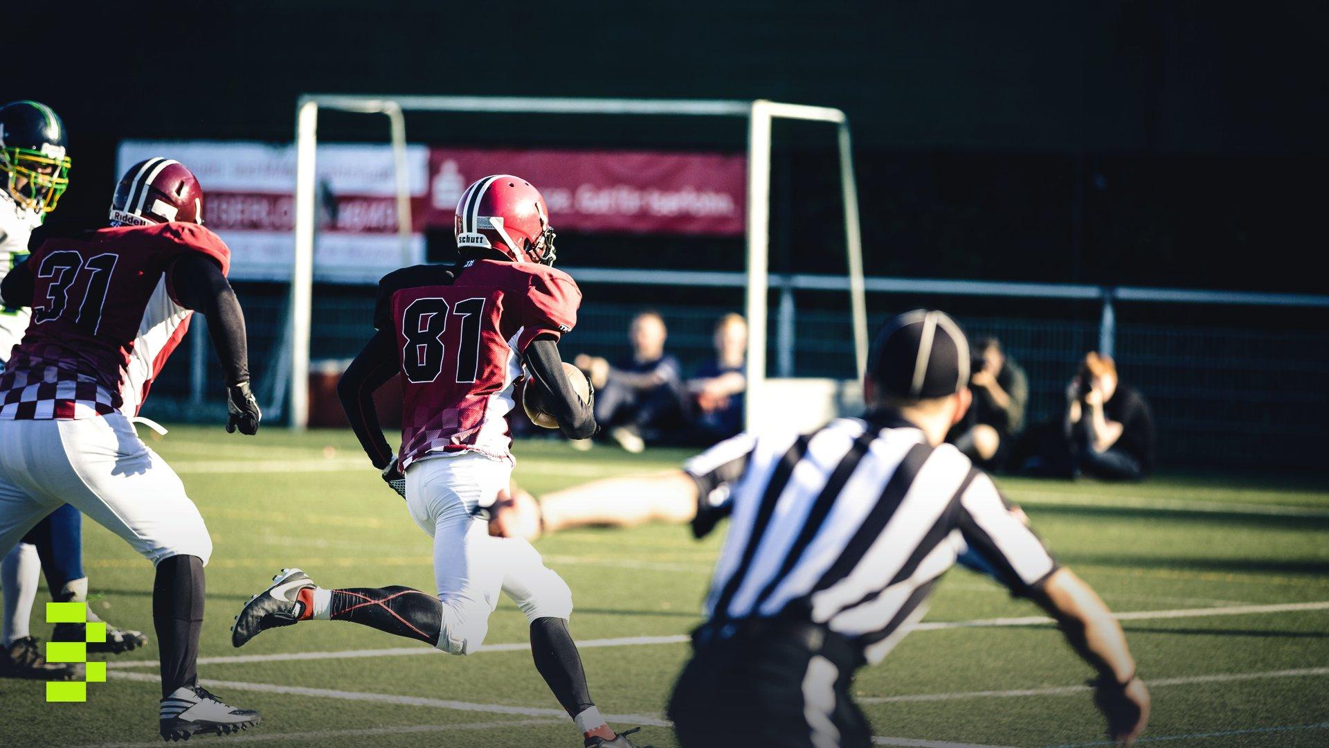 Intense action shot of American football players running on a field during a competitive game.