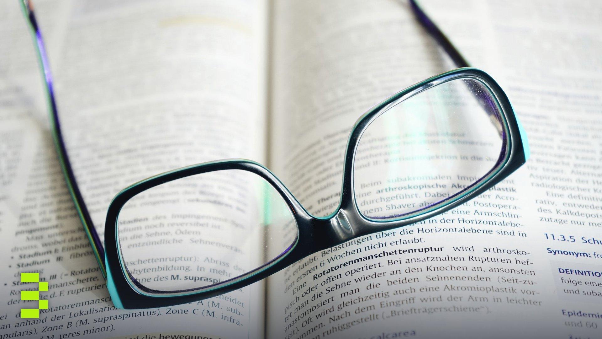 Reading glasses resting on an open textbook.