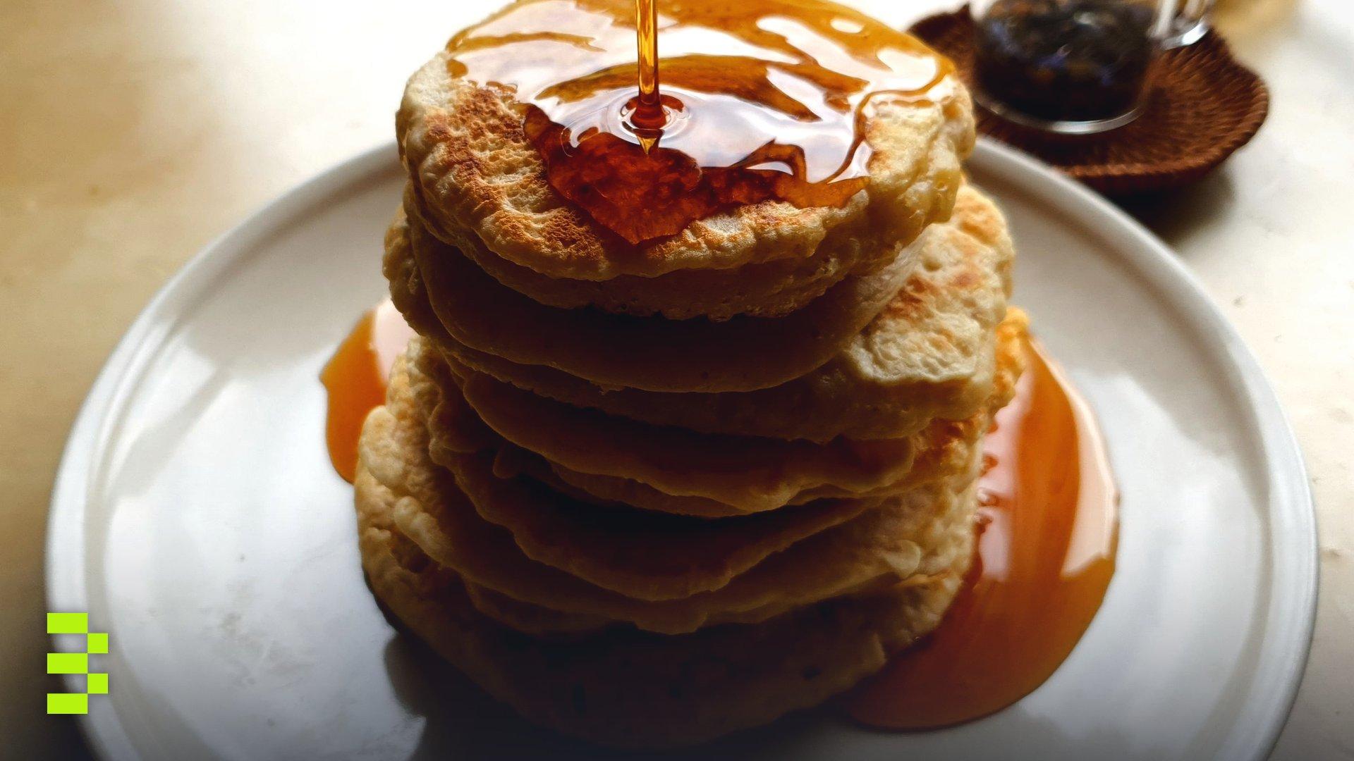 Delicious pancakes stacked high, drenched in syrup.