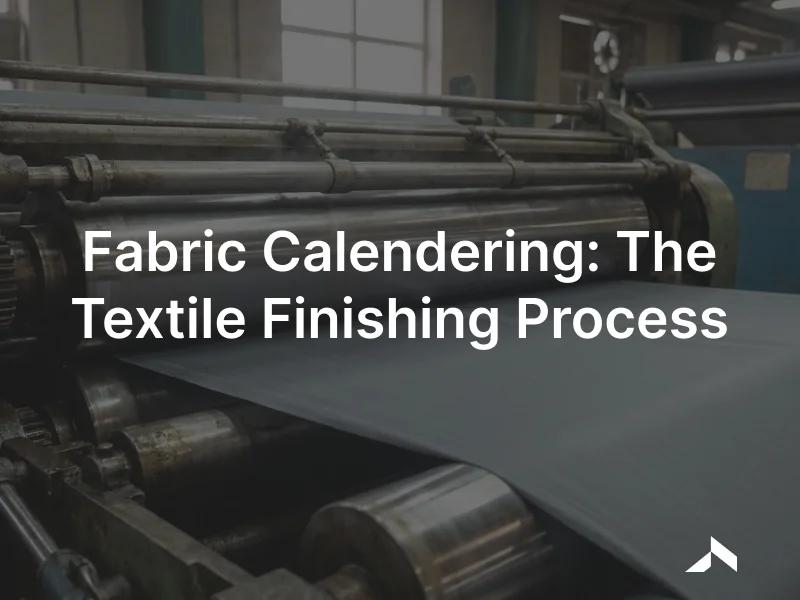 Rollers of an industrial textile calendering machine pressing a smooth length of fabric under bright light