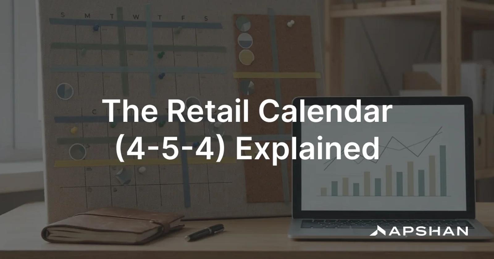 A wall planning calendar of weekly blocks beside a laptop showing a retail sales chart on a desk
