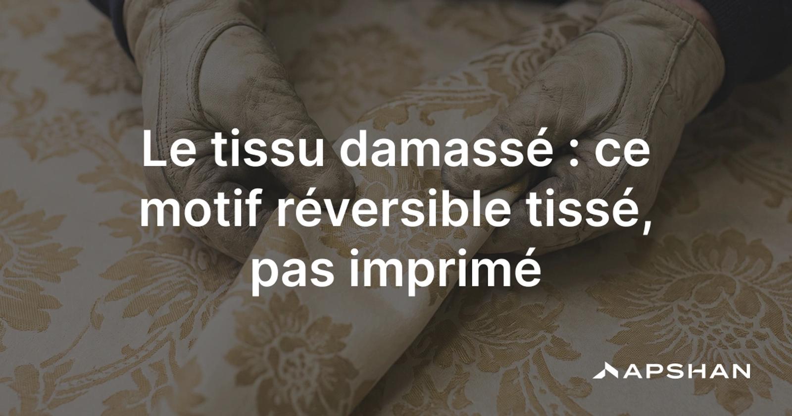 Gros plan sur un tissu damassé blanc: un motif floral tissé, révélé par le contraste entre satin brillant et fond mat.
