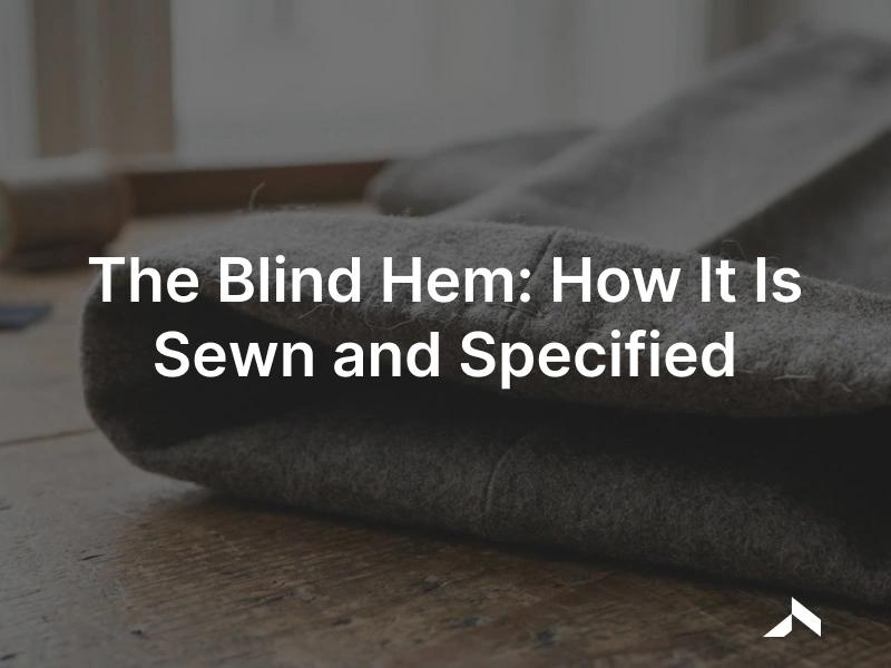 Close-up of a tailored trouser hem turned up, with a nearly invisible blind-hem stitch catching a thread of the wool