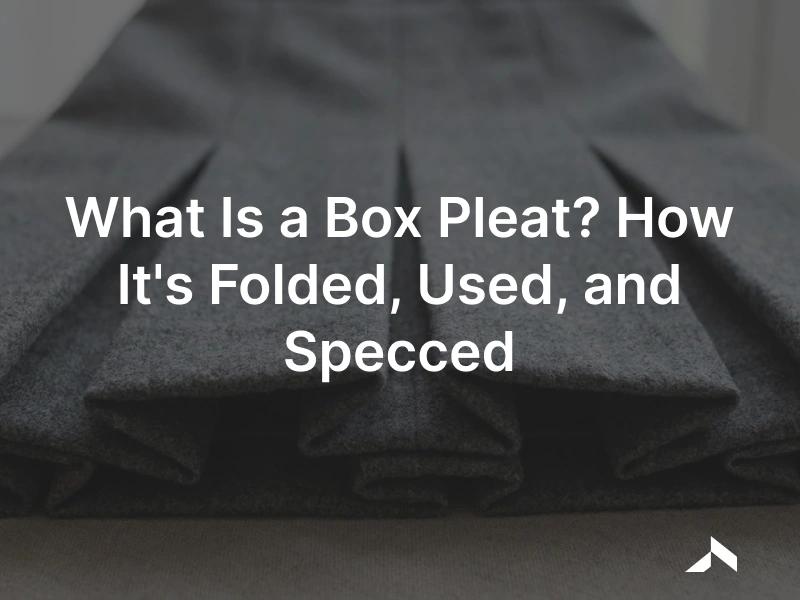 Close-up of crisp pressed box pleats on a grey wool skirt, the outer folds facing away from each other in an even row