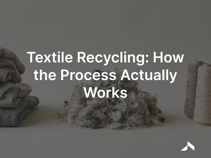 Textile recycling process: sorted used clothing shredded into recovered fibres beside spools of new yarn on a neutral surface