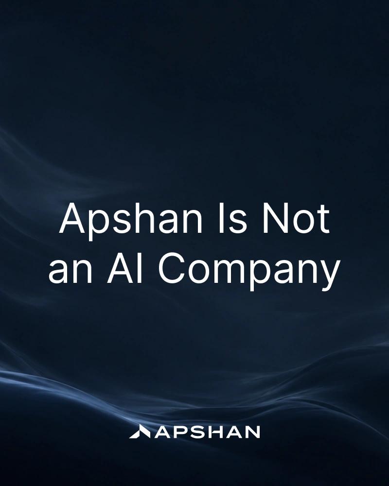 Dark navy backdrop with pale-blue smoke trails. Large white text 'Apshan Is Not an AI Company' above the Apshan wordmark.