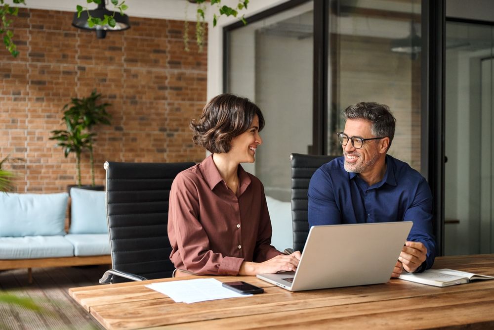 couple at home desk looking at laptop