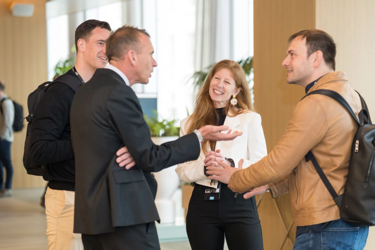 Four business professionals networking and shaking hands in a bright conference venue lobby