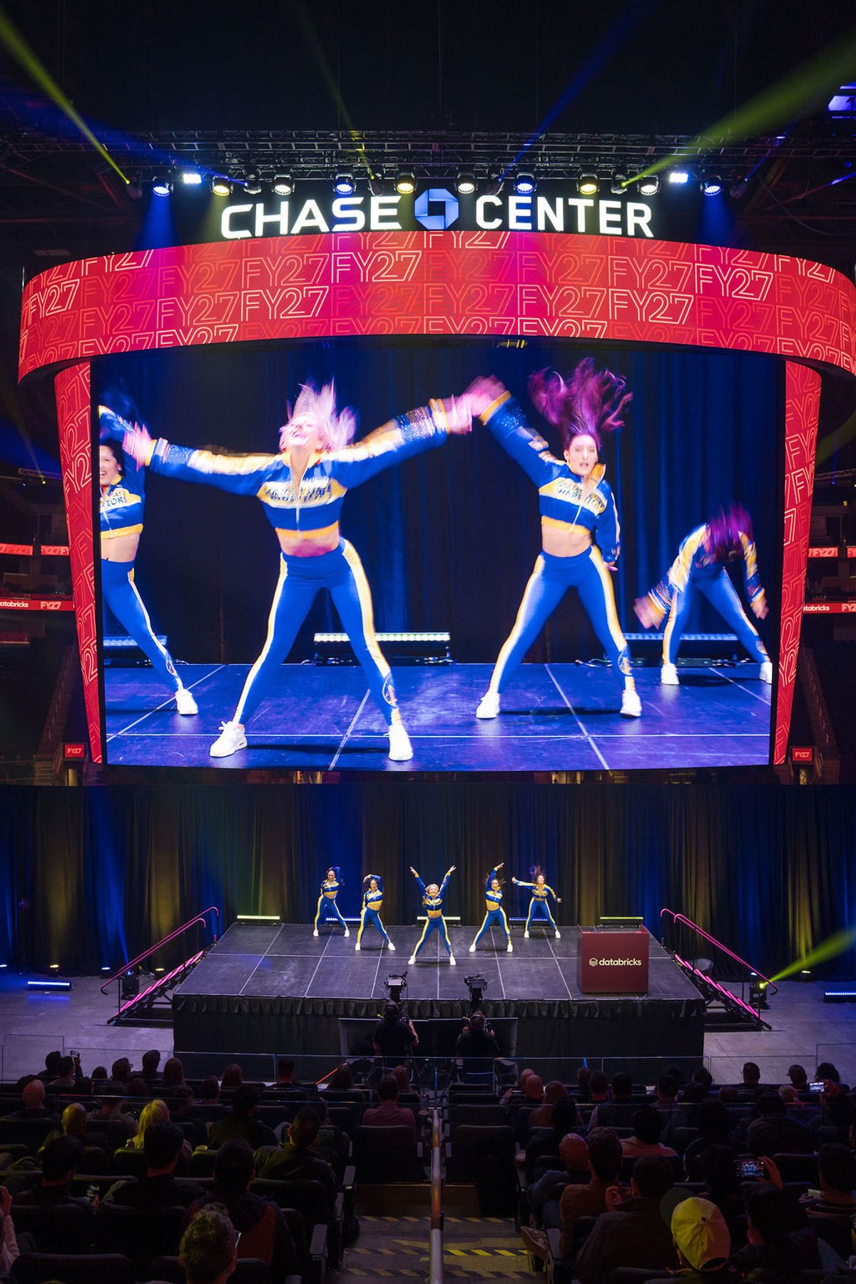 Cheerleaders performing on stage at Chase Center with large video screen showing close-up of routine