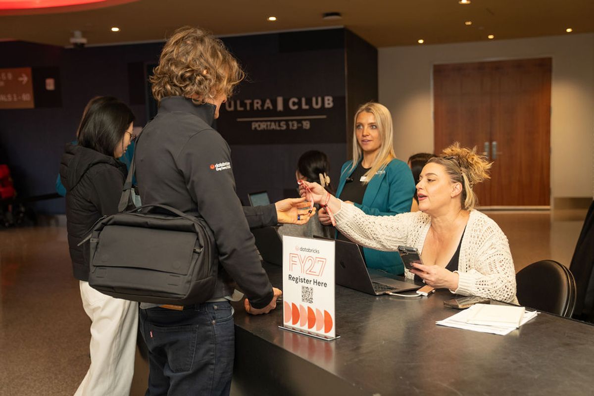 Attendees register at a conference check-in table with staff members assisting at an event venue.
