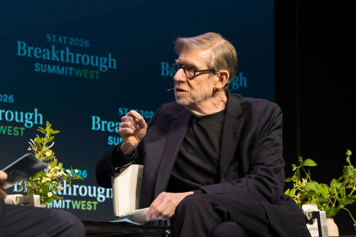 Speaker in black suit and glasses gesturing during panel discussion at Breakthrough Summit West event